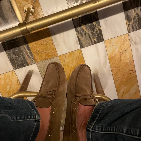 Suede driving shoes on a marble chequerboard with brass rails