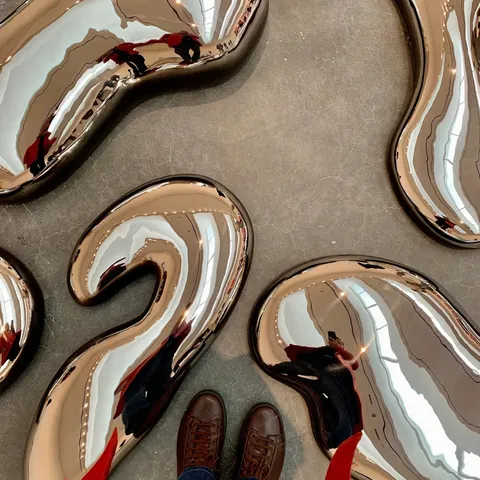 Brown sneakers among mirrored sculptures on a concrete floor