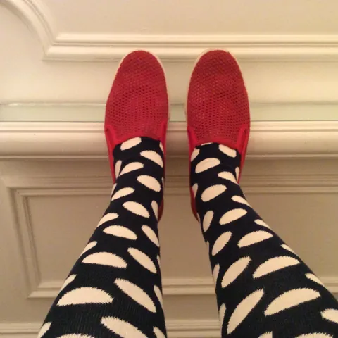 Red mesh slip-ons and polka-dot socks against white panelling
