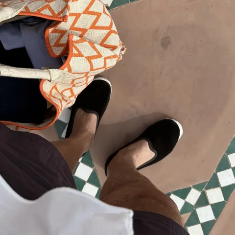 Black slip-ons on terracotta tiles with a green and white border
