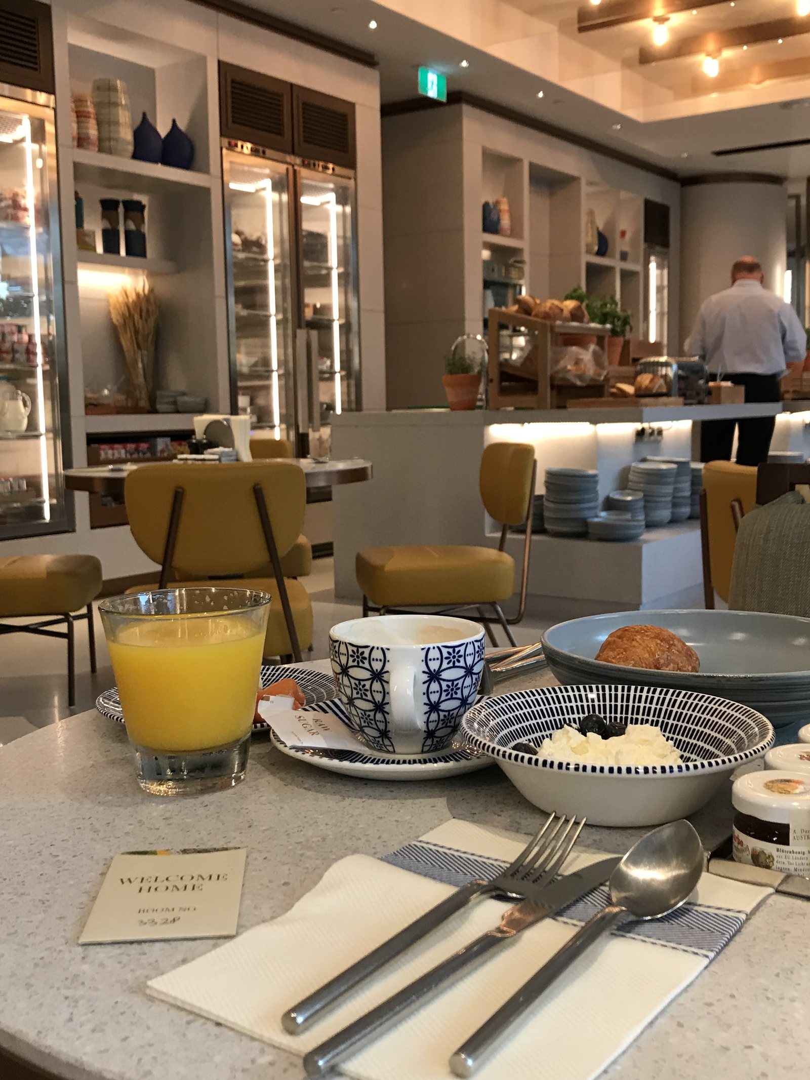 A breakfast room with mustard chairs, a long counter and glass-fronted cabinets