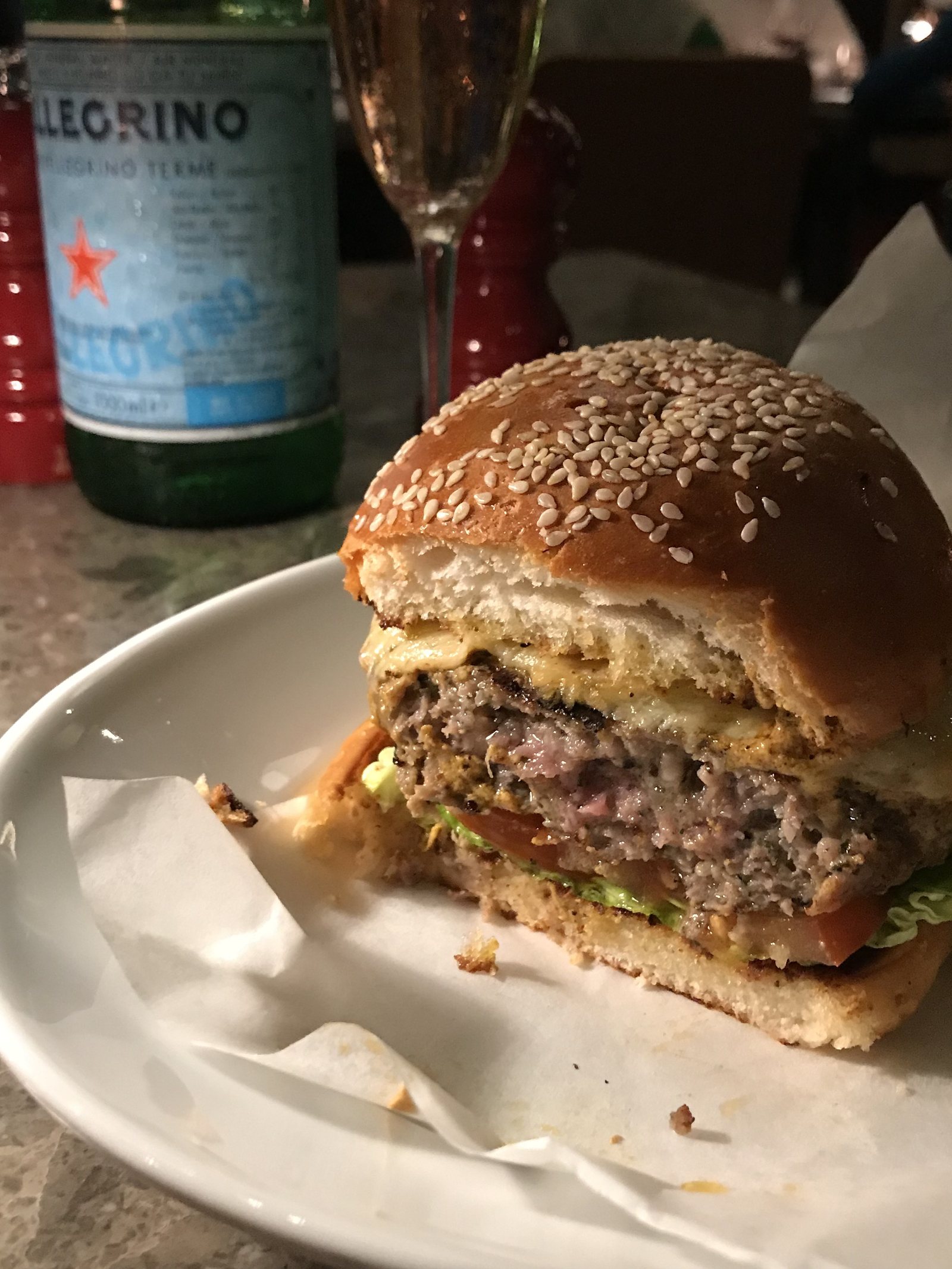 A sesame burger cut through, with fries on the side on a white plate