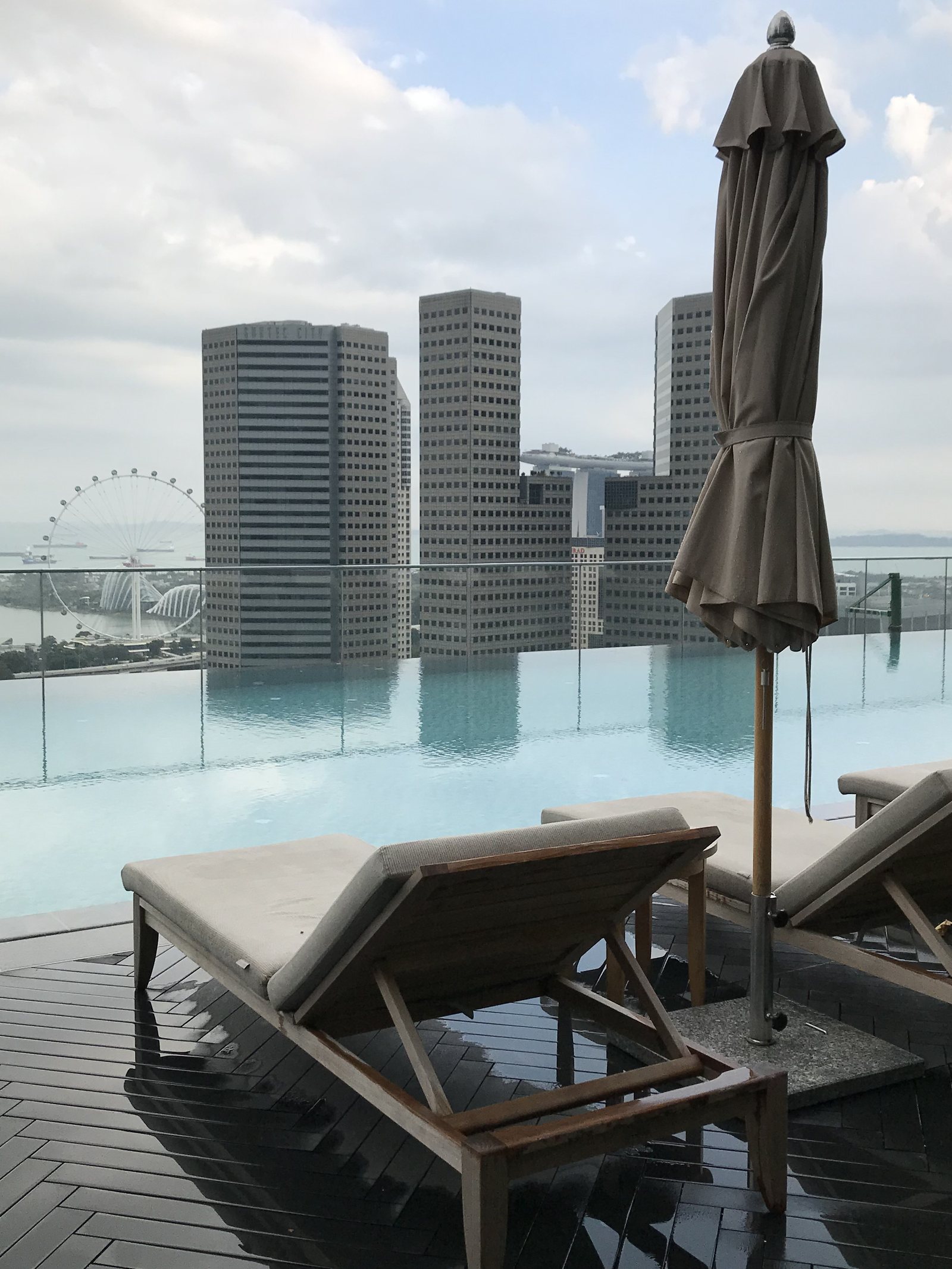 Loungers under a furled parasol at the edge of the infinity pool, the skyline beyond