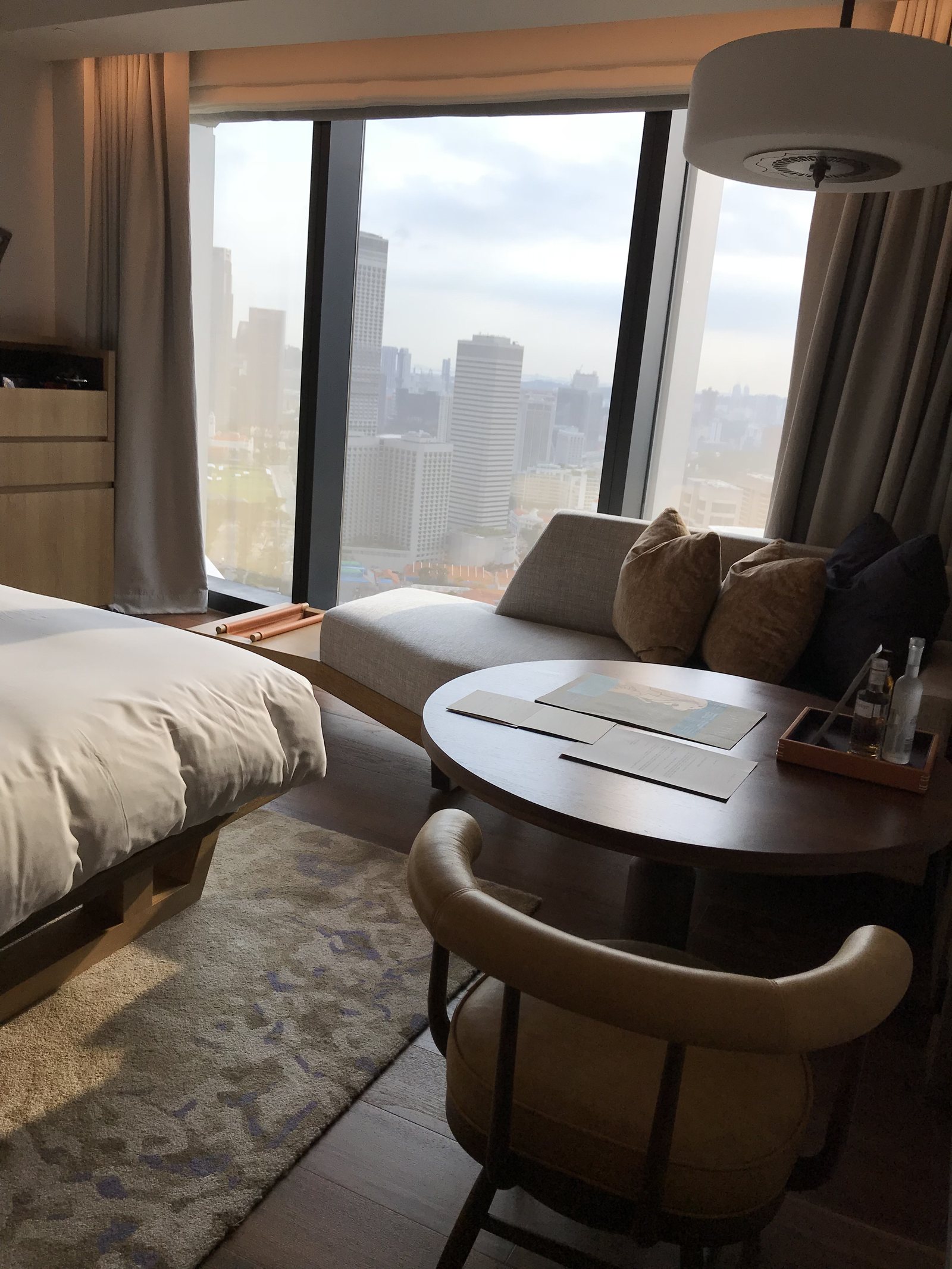 A room with floor-to-ceiling glass looking onto the towers of the city, a daybed along the window