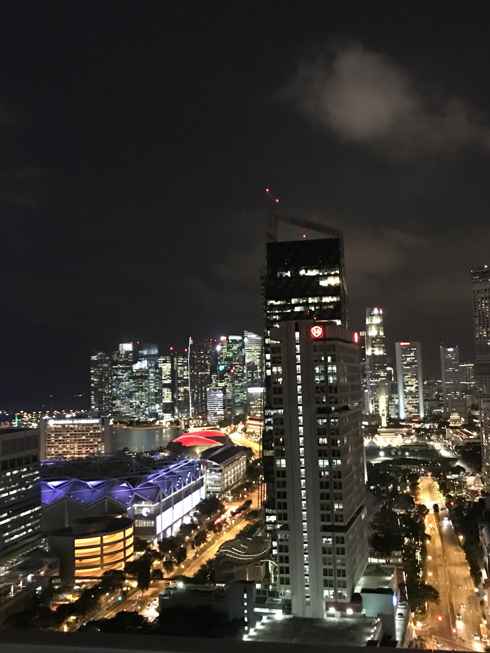 The lit towers of central Singapore seen at night from high up, traffic moving below