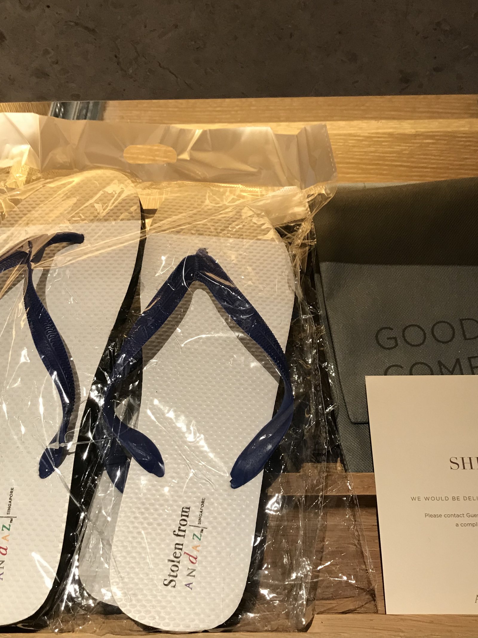 A pair of flip-flops printed Stolen from Andaz, wrapped, beside a card reading Shine On