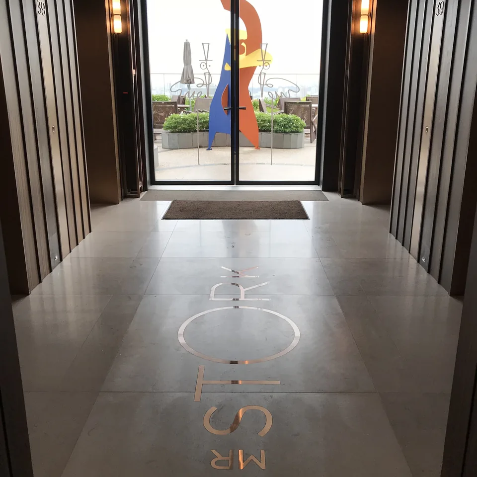 A corridor with MR STORK inlaid in brass across the stone floor, open doors at the end