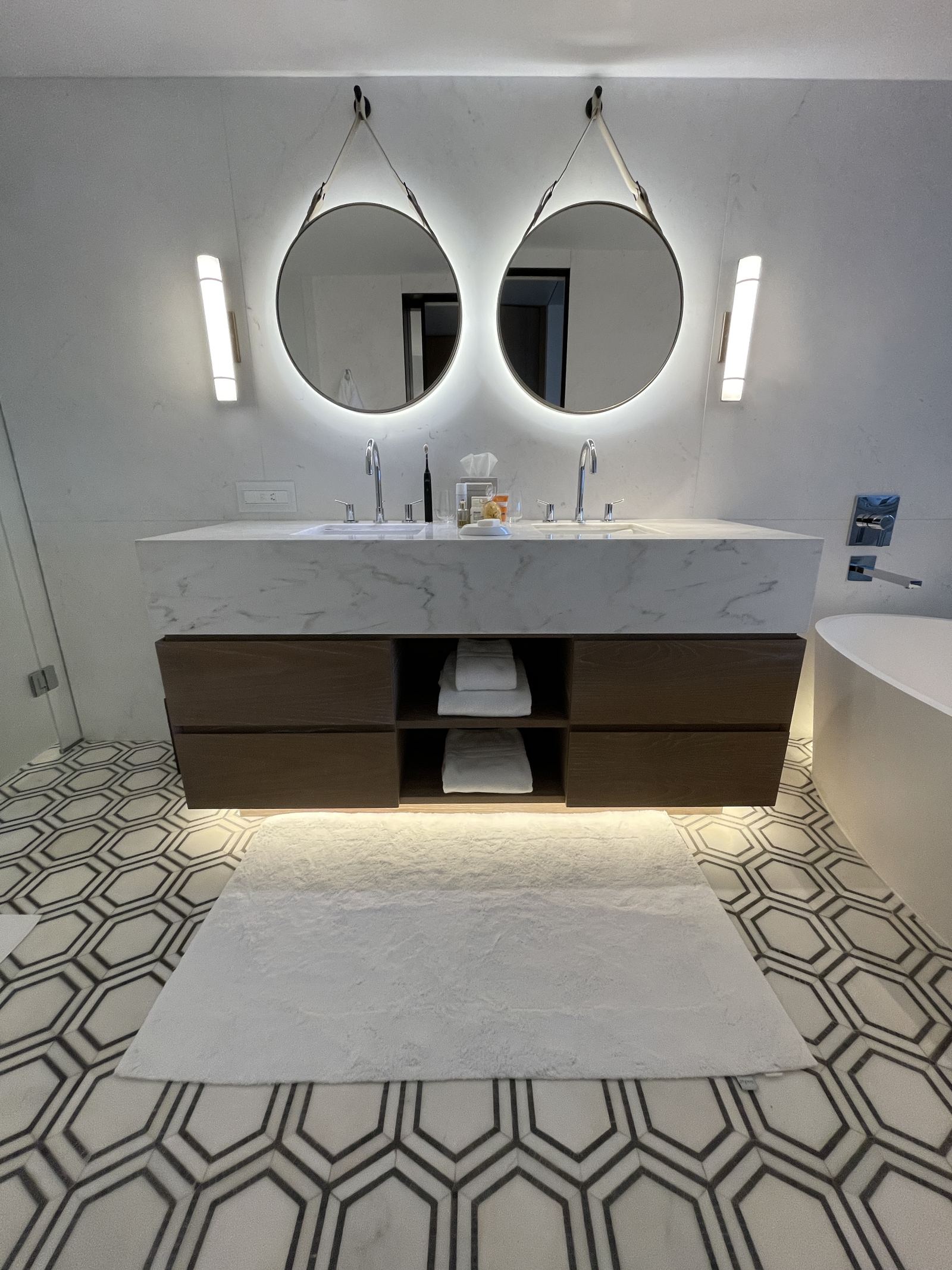 The bathroom of a Nafsika room, twin round mirrors above a stone vanity