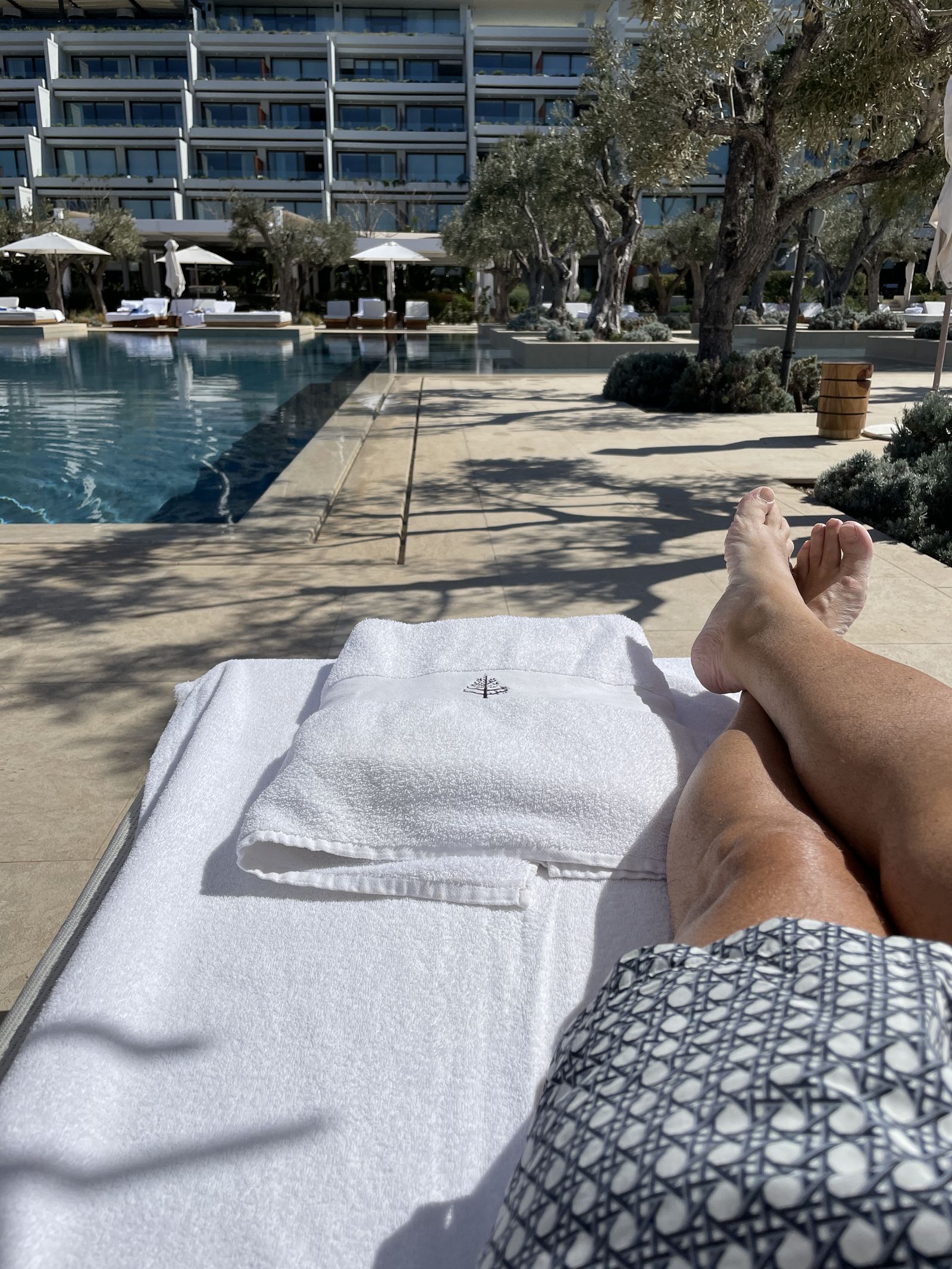 Bare feet on a daybed under a parasol, looking out to the Saronic Gulf at Four Seasons Astir Palace