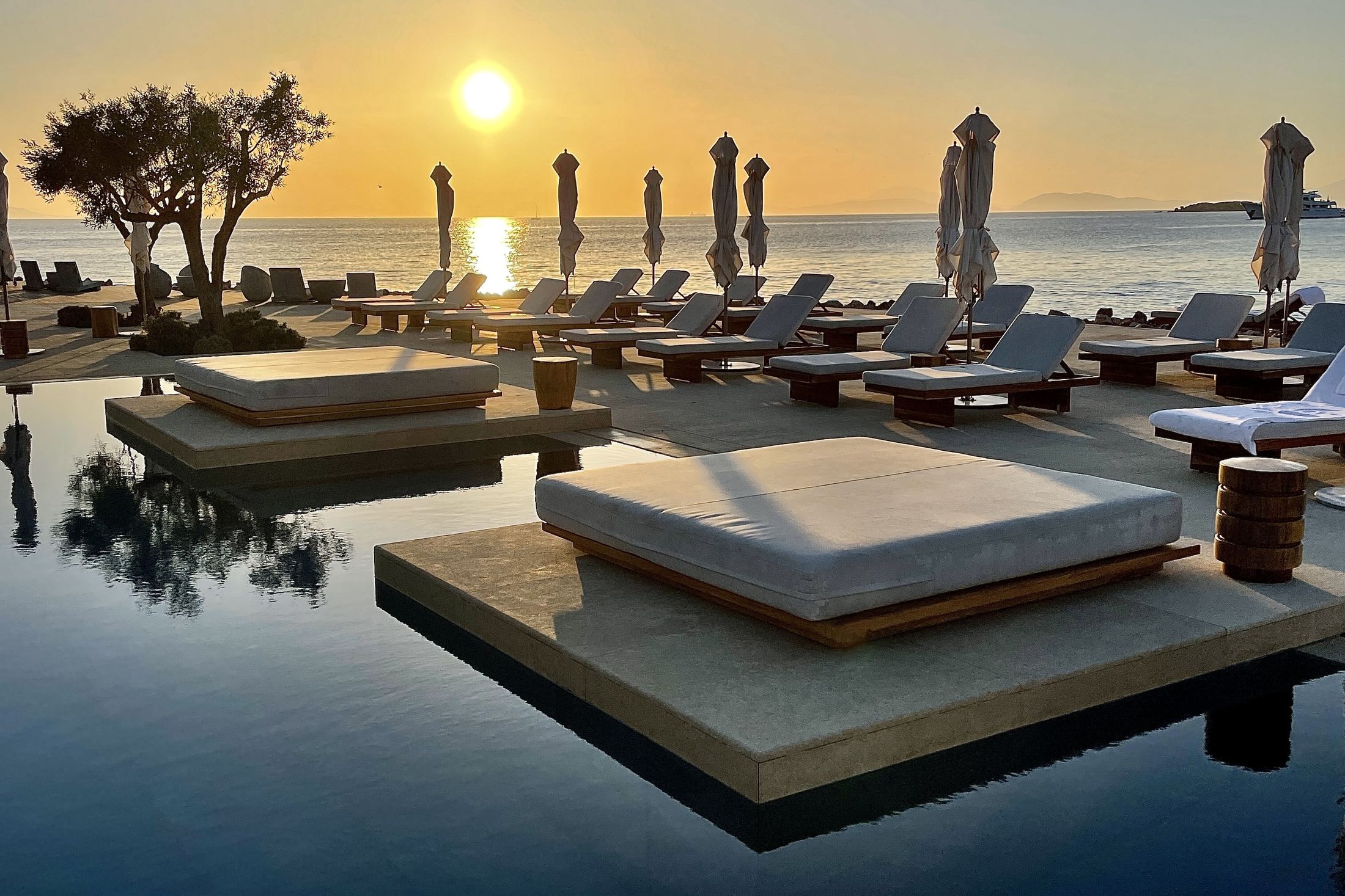 Floating daybeds on the infinity pool at sunset, the gulf beyond