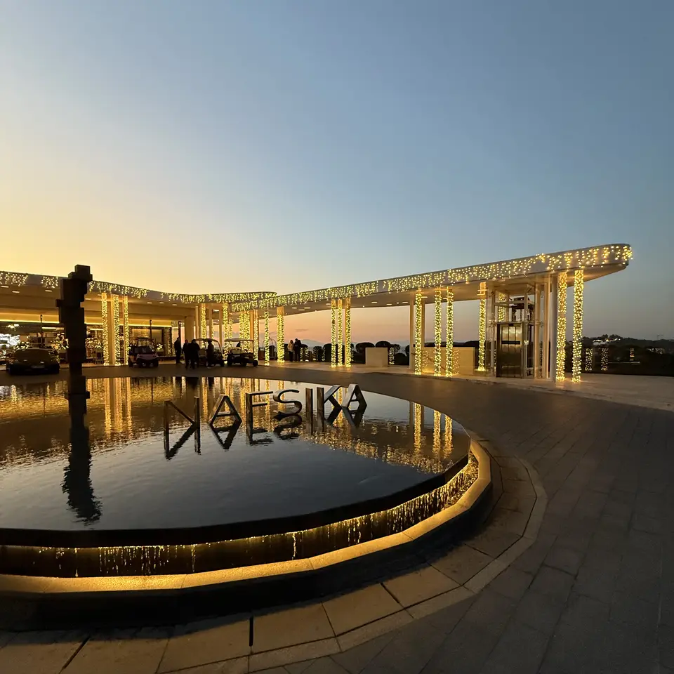The Nafsika building reflected in the entrance pool at dusk
