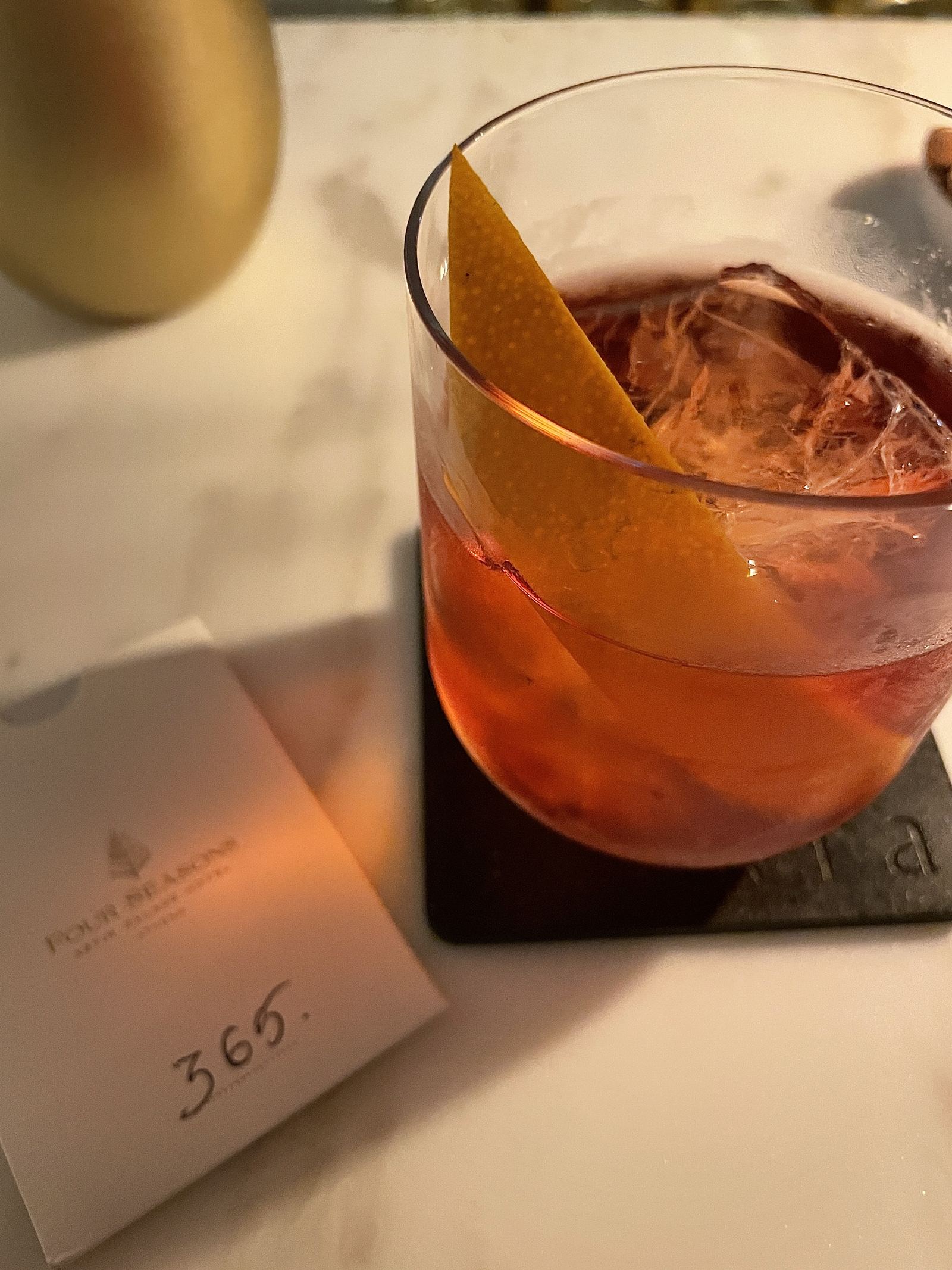 A negroni on the bar at Avra beside a Four Seasons card