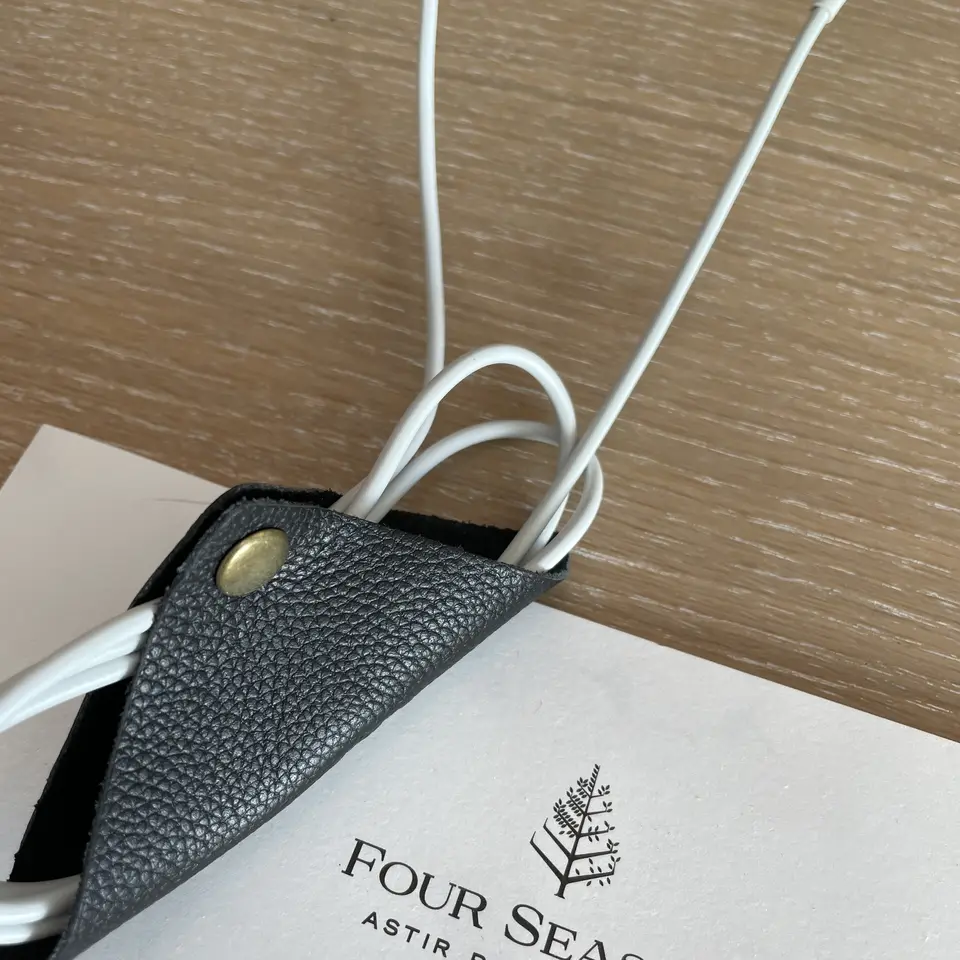 A Four Seasons Astir Palace notepad on the desk beside a charging cable