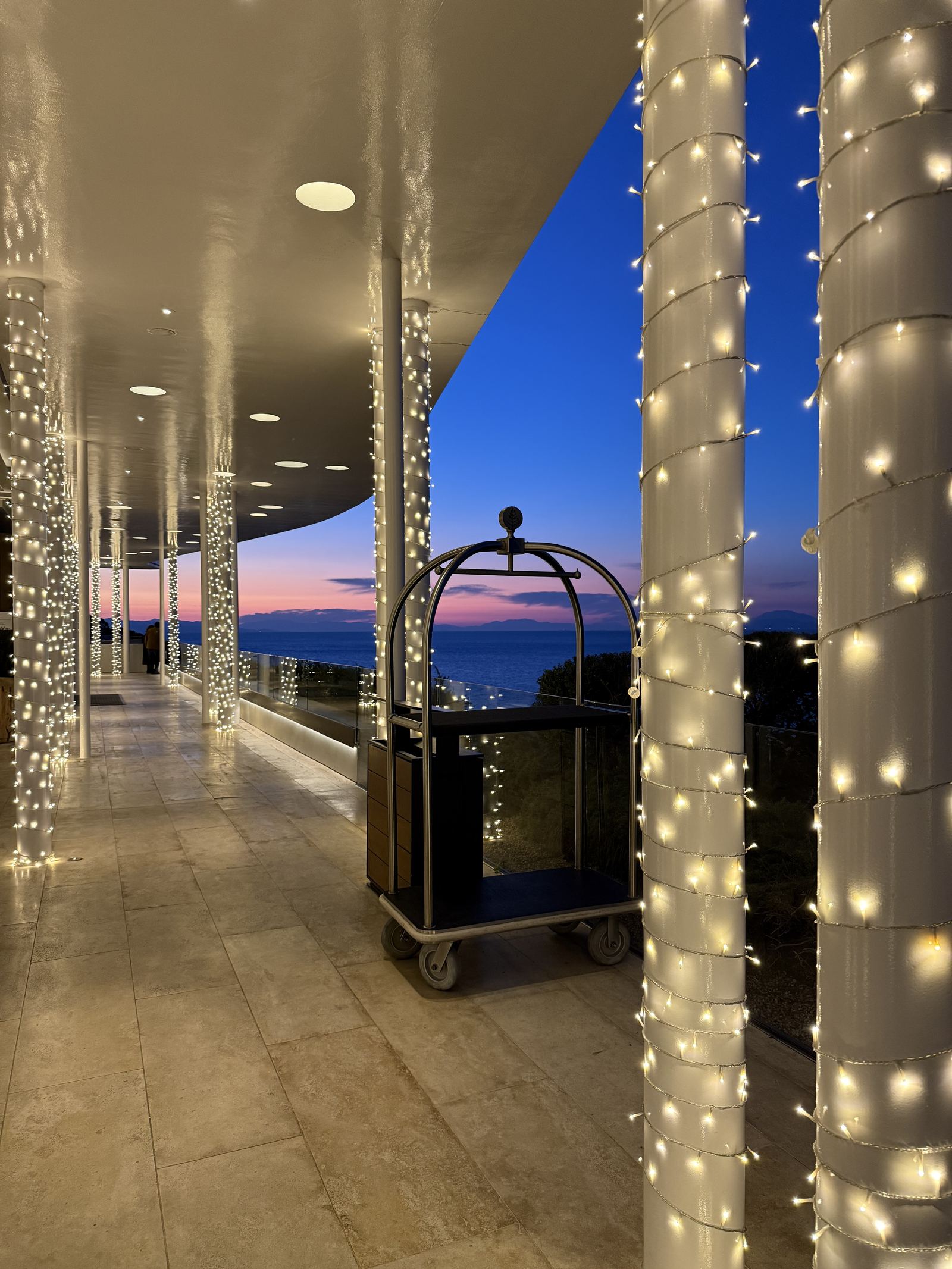 The colonnade at Four Seasons Astir Palace at dusk with its columns wrapped in lights