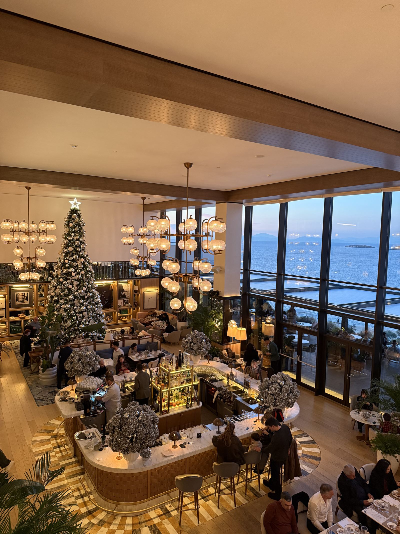 The Arion lounge with a decorated tree, chandeliers and the sea beyond the glass