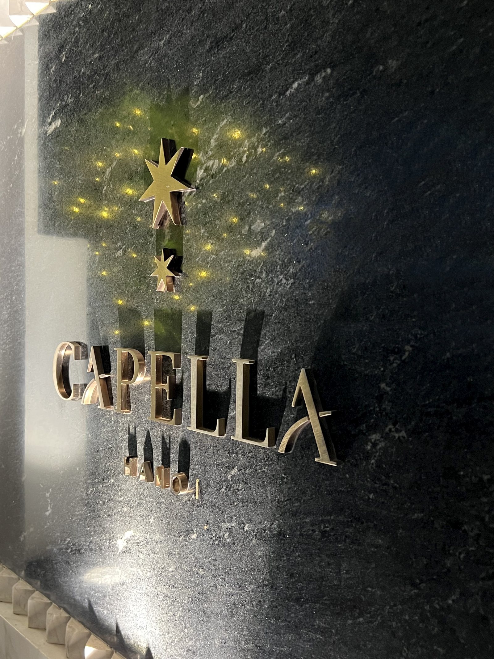 The hotel's name in brass letters on a dark stone wall, lit from above with small star-shaped lights