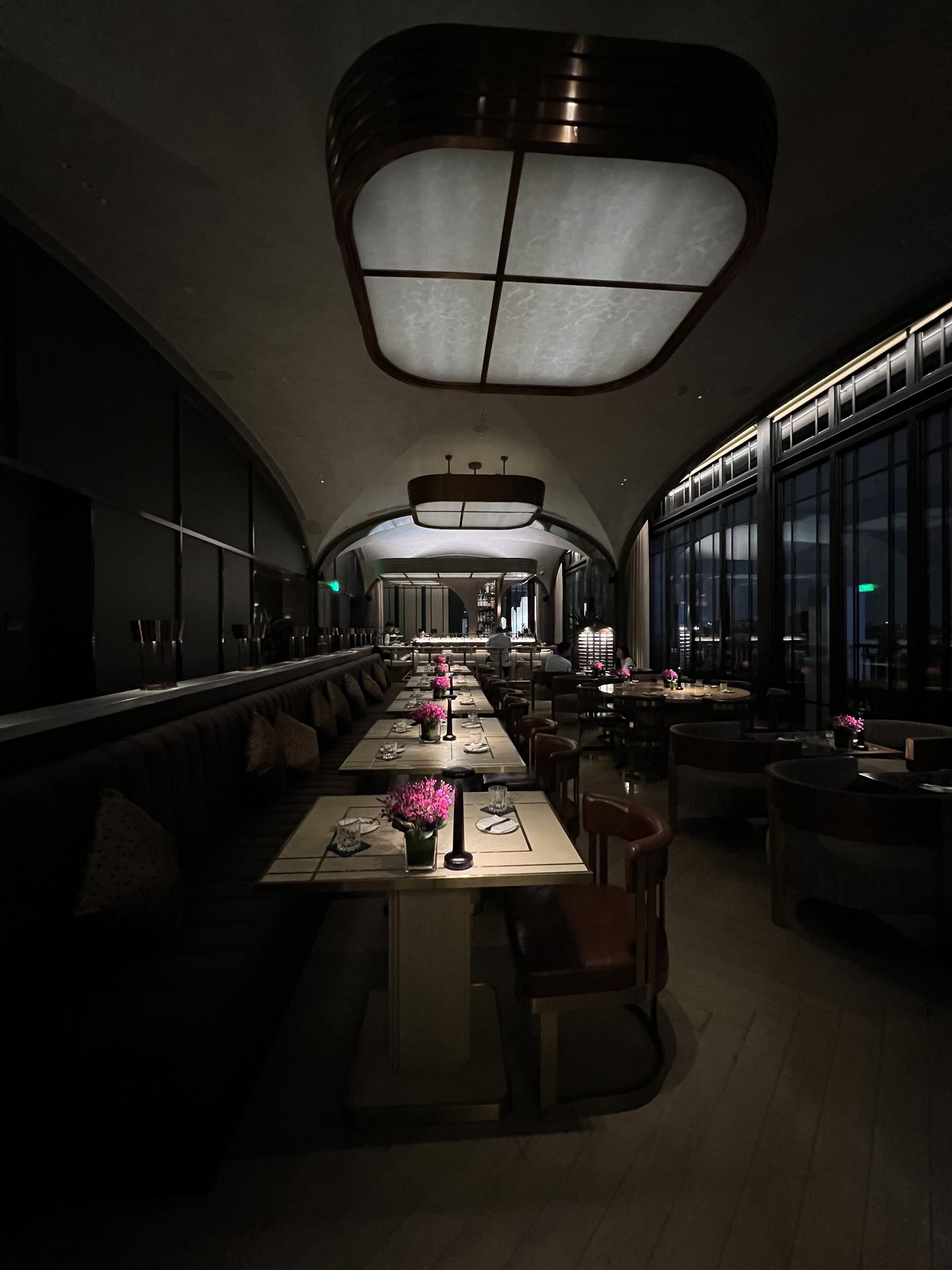 A long narrow dining room with a curved ceiling, banquettes down one side and tables laid in a row