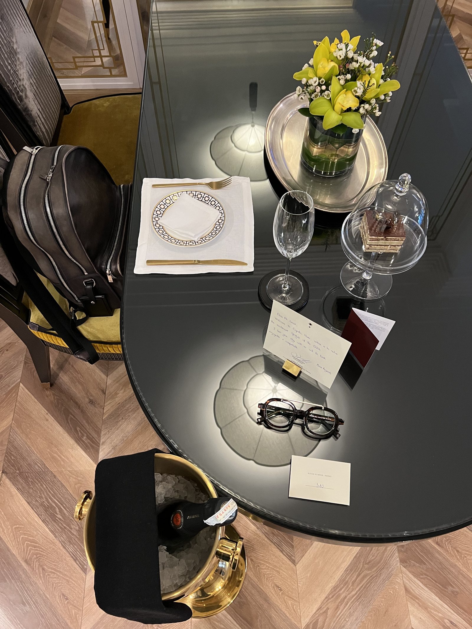 The same oval welcome table seen from above, with the glass, the card, the spectacles and the ice bucket