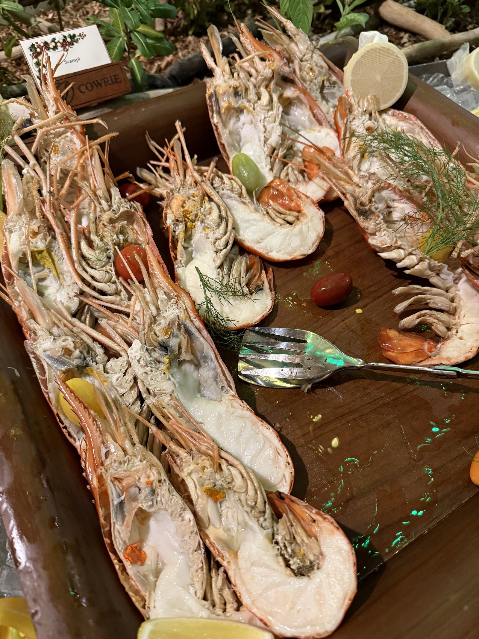 A long timber tray of grilled lobster and prawns with lemon and herbs at Cowrie restaurant