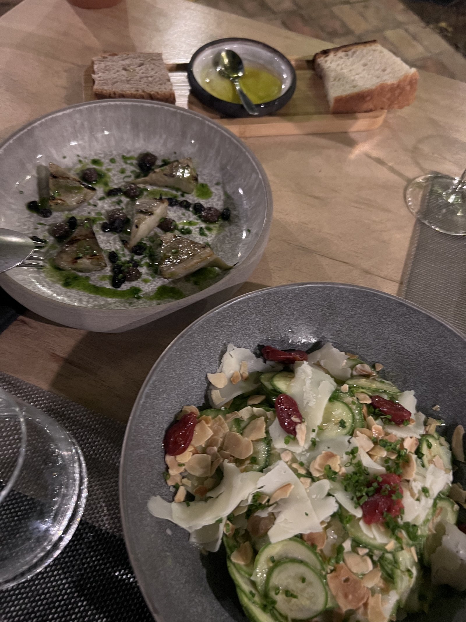 Two plates at Dexamenes, a dish of thinly sliced fish with herbs and a salad of greens with shaved cheese and tomato