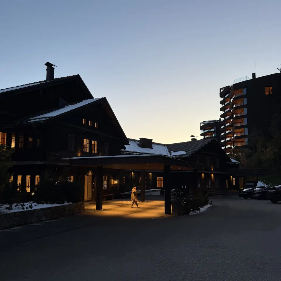 The lit porte-cochere at Forestis at dusk with the old timber house on one side and the new wing on the other