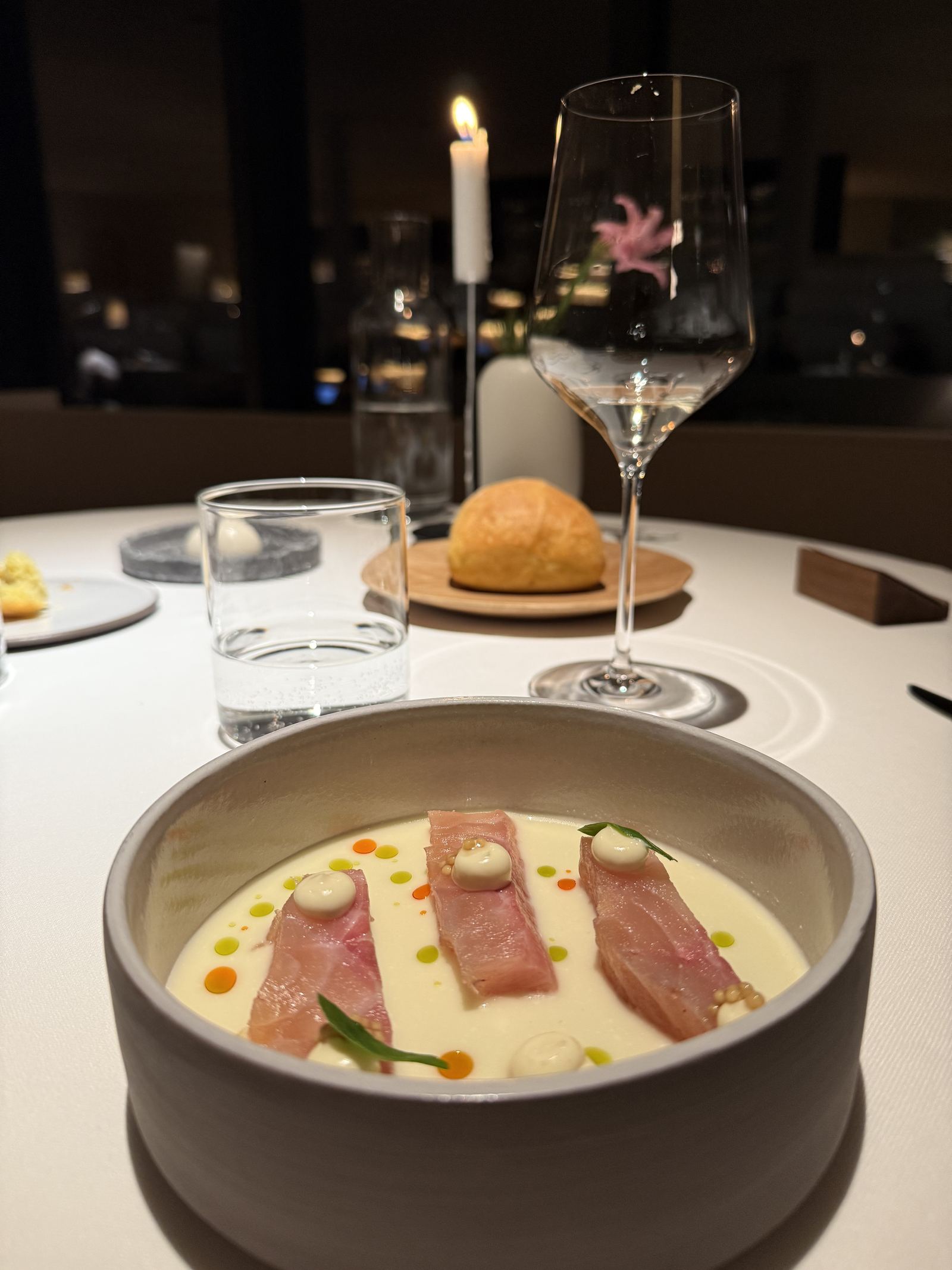A plated fish course by candlelight at FORESTIS