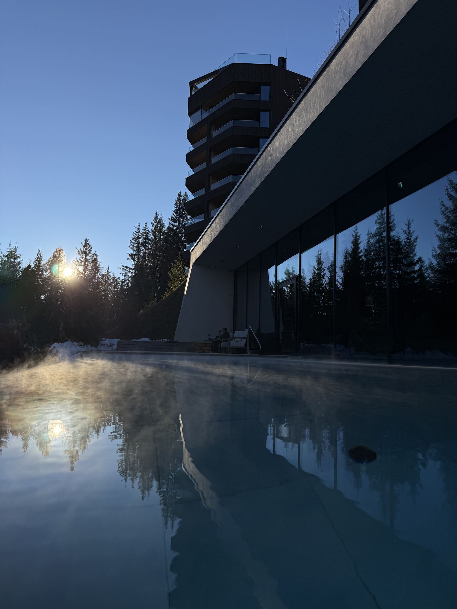 The outdoor pool at FORESTIS at sunset, the Dolomites standing behind it
