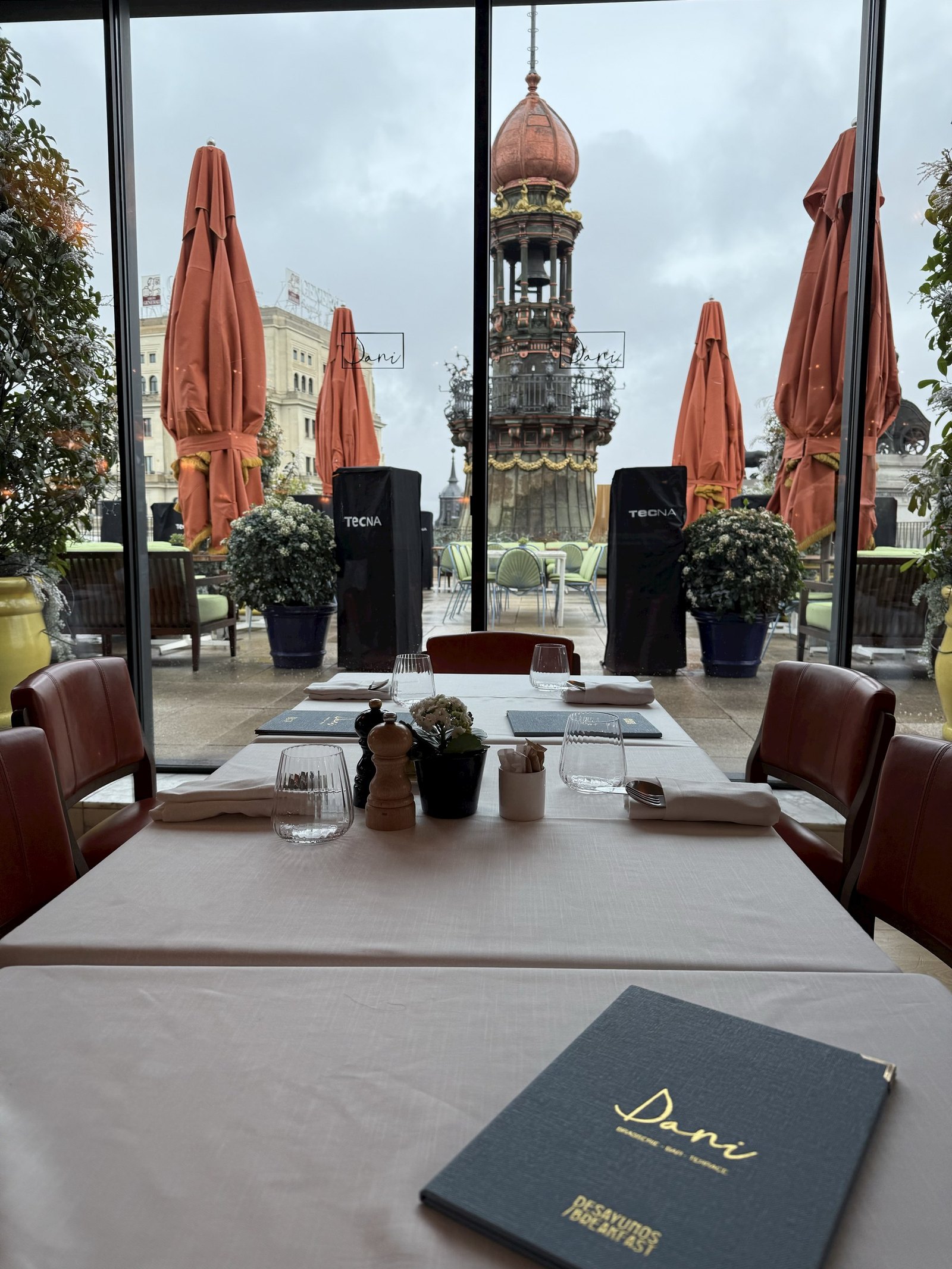 A table laid by the window of the brasserie with a domed tower outside in grey weather