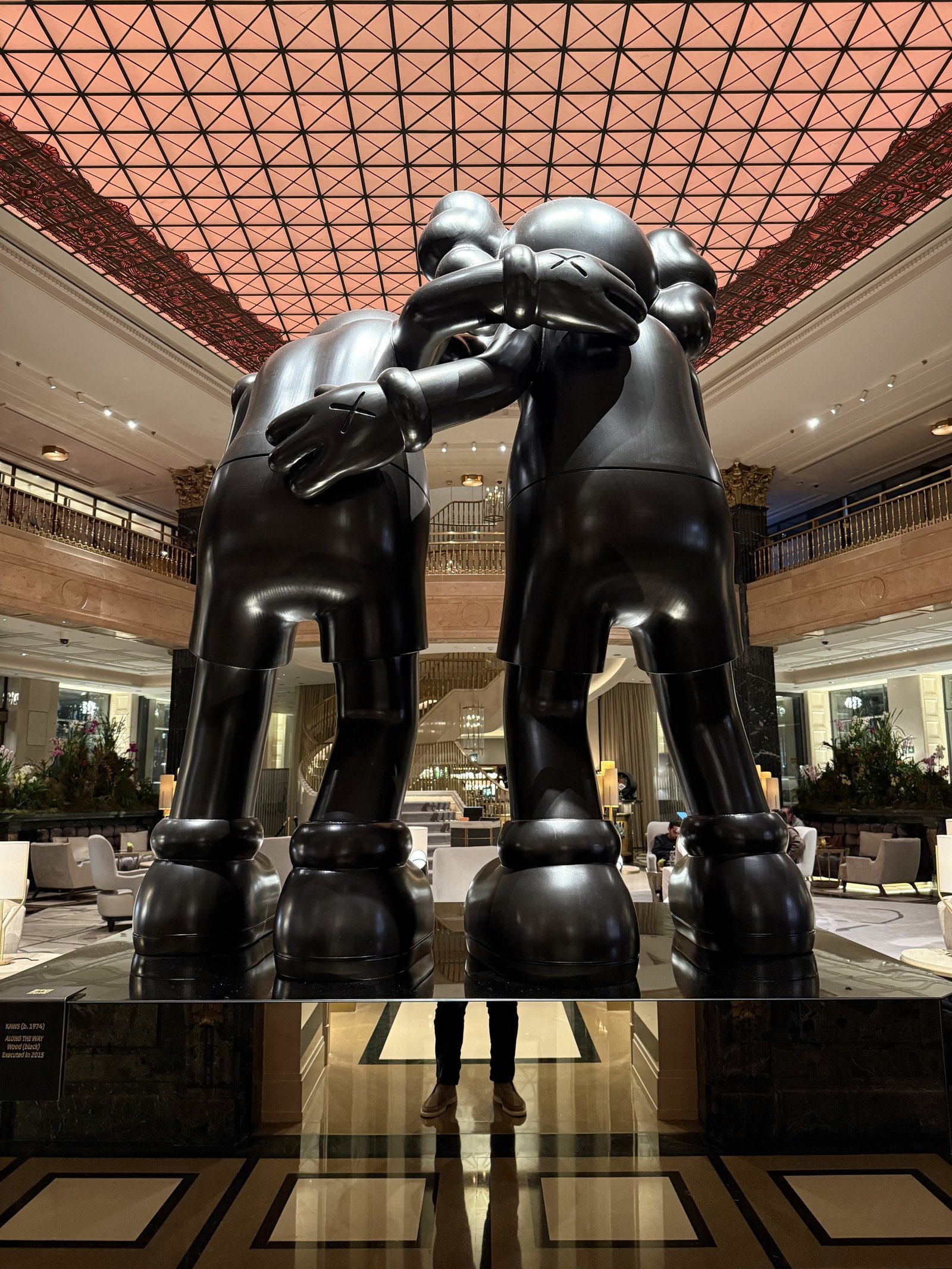 Two large dark figures standing under the glass roof of the galleria