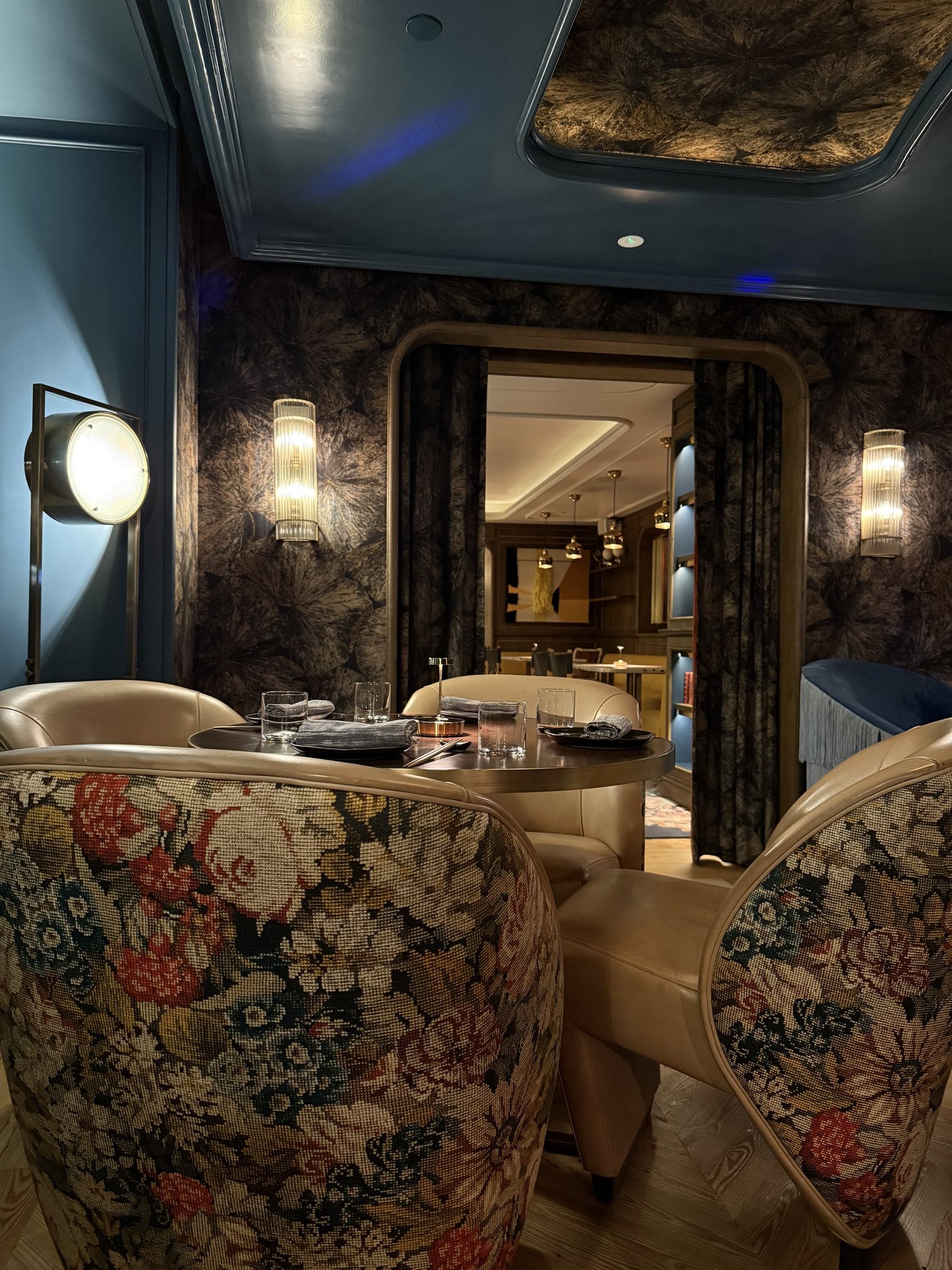 The dining room at Isa with floral armchairs and dark marble walls