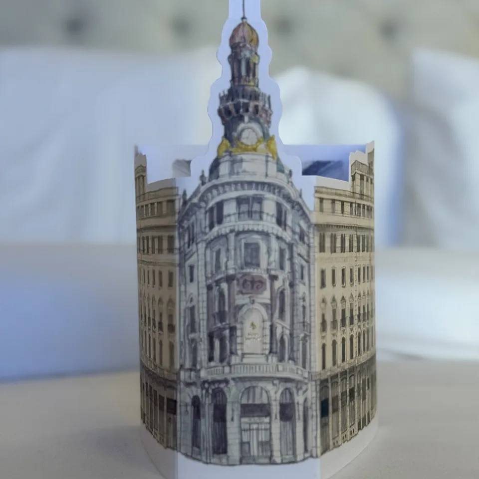 A paper model of the hotel building standing on the bed