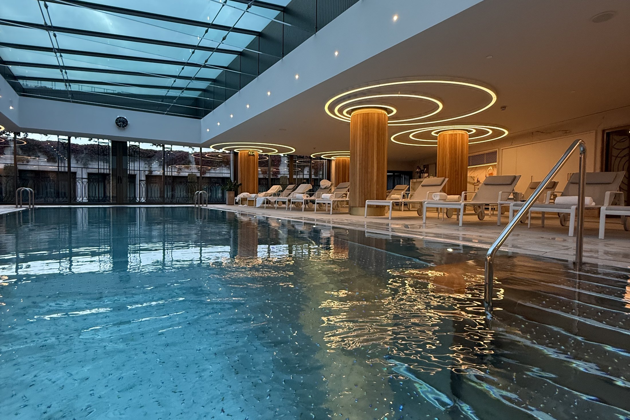 The indoor pool at Four Seasons Madrid under a long glass roof with loungers alongside