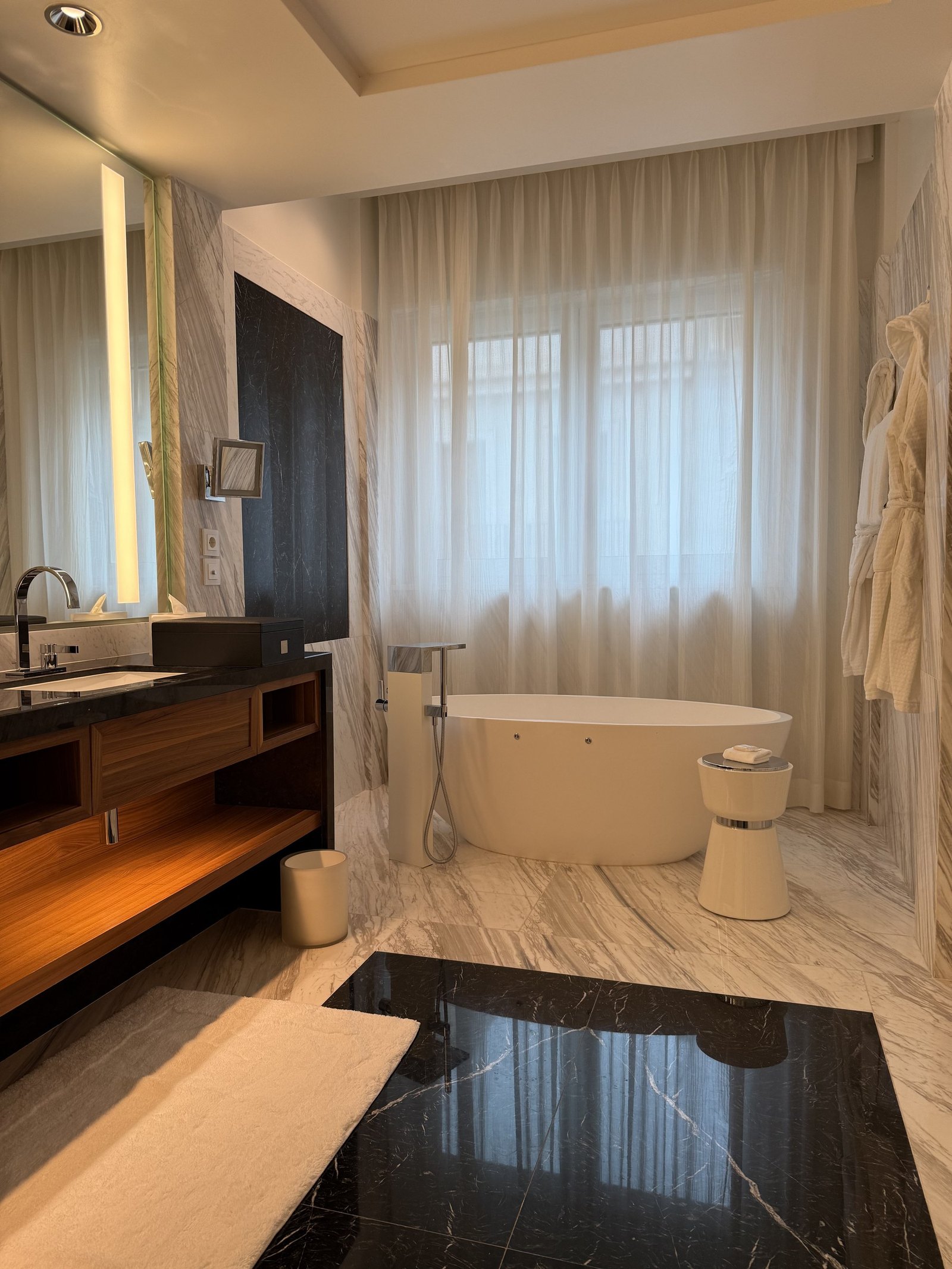 The bathroom of an Executive Suite with a freestanding tub, long vanity and dark stone floor