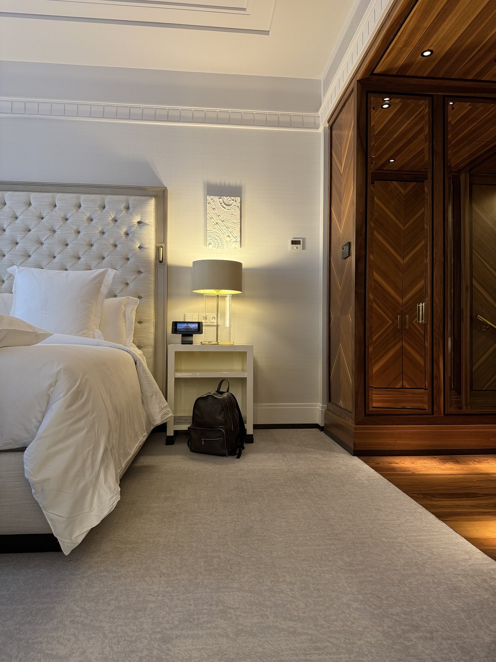 The bed in an Executive Suite with a tufted headboard and a bag on the floor