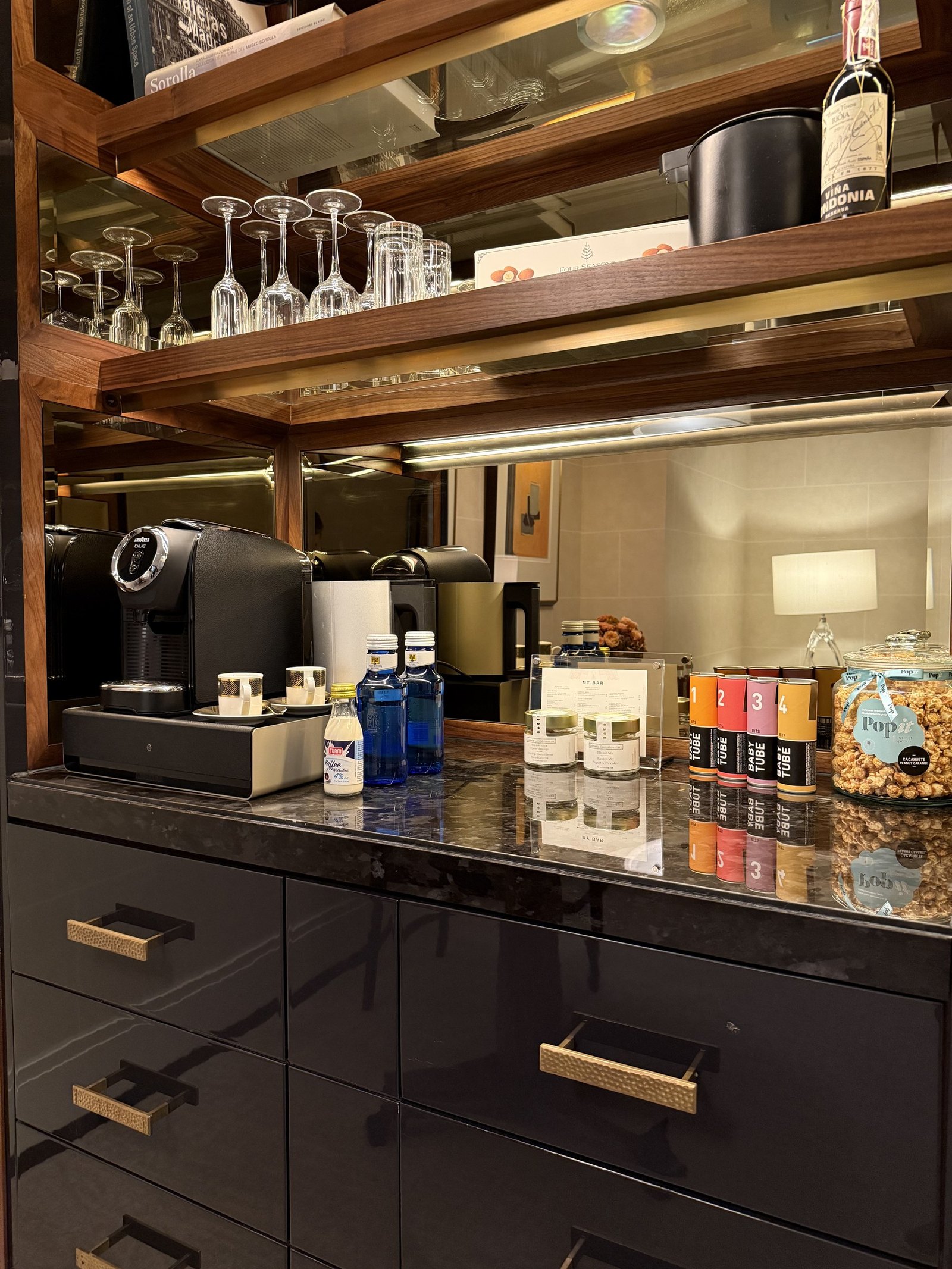The pantry of an Executive Suite with a coffee machine and glassware on dark cabinetry