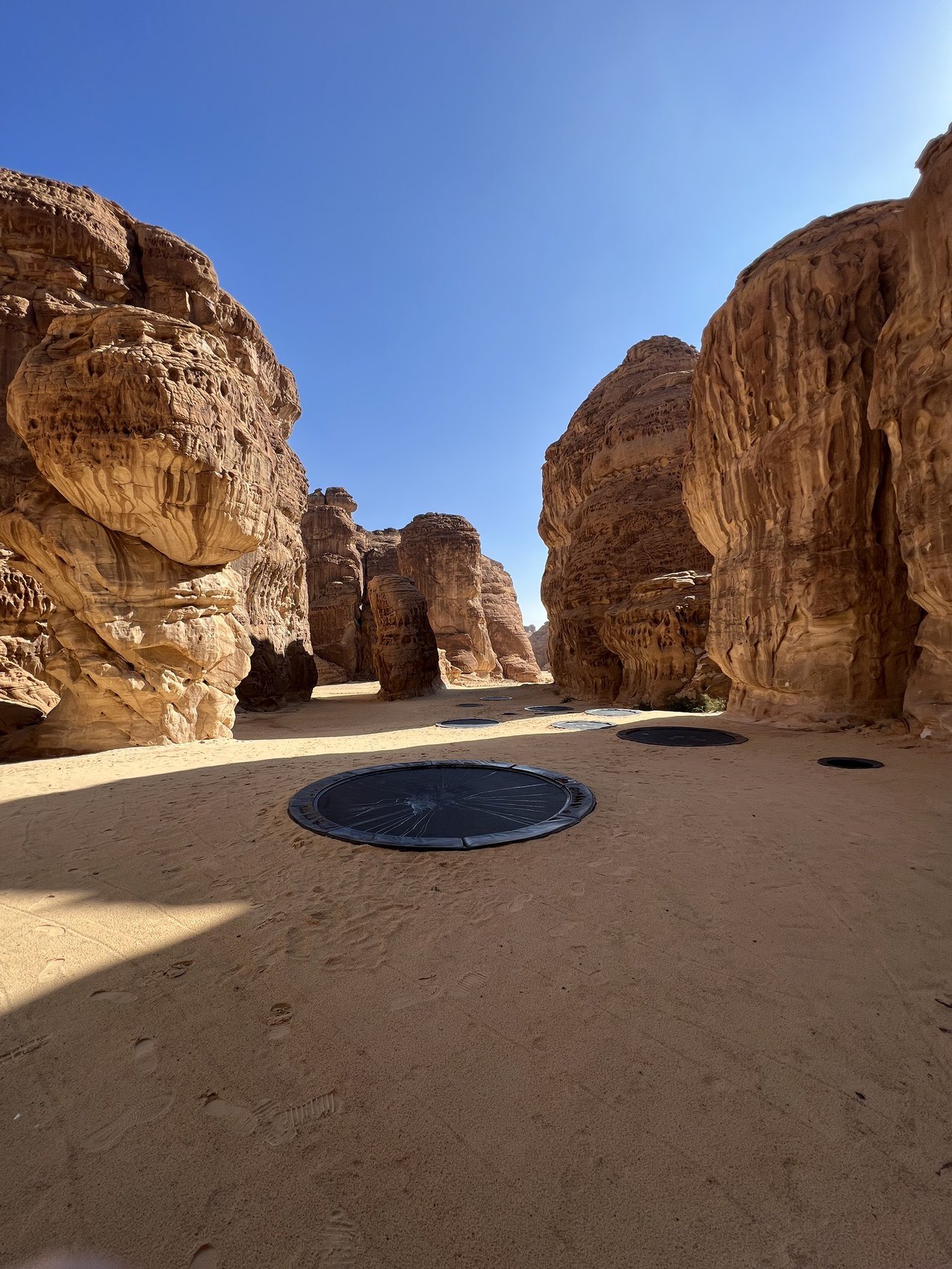 Elastic nets set into the sand of a rock amphitheatre at AlUla under a clear blue sky