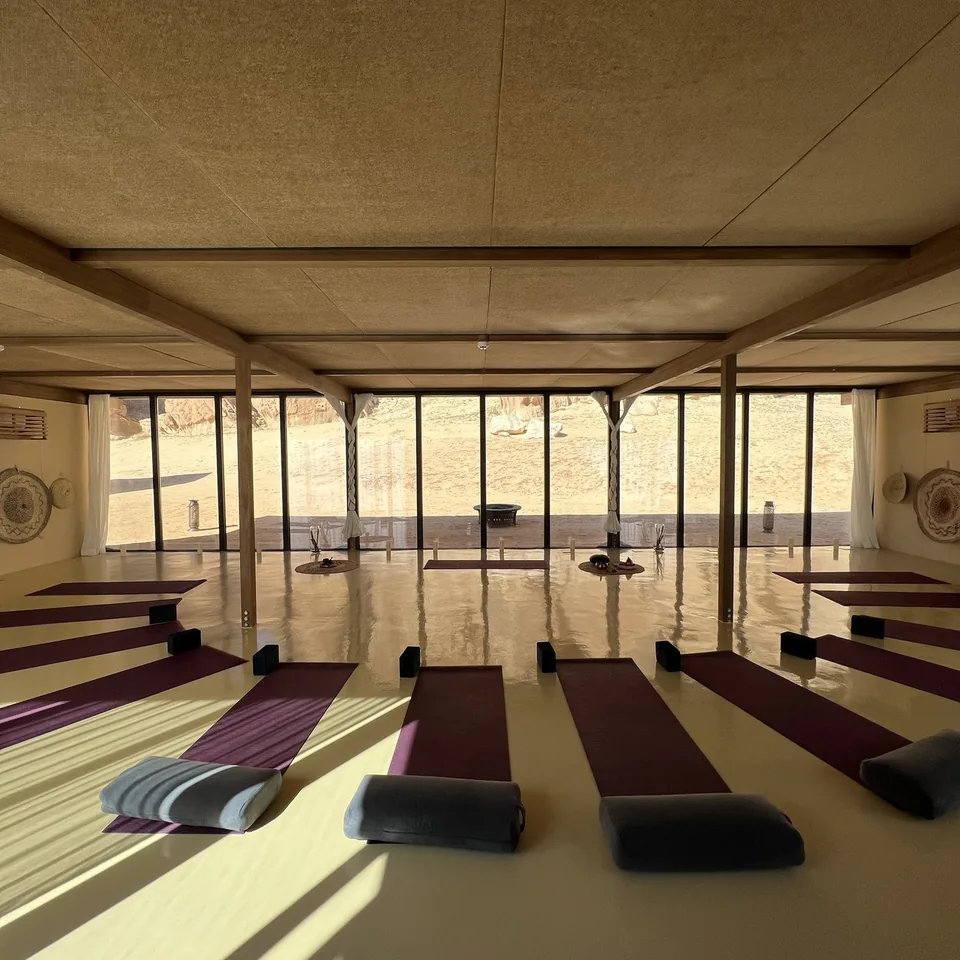 Mats and bolsters laid out in an open sided tent looking onto the desert