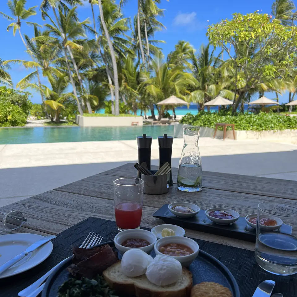 A breakfast table set by the pool with the lagoon beyond