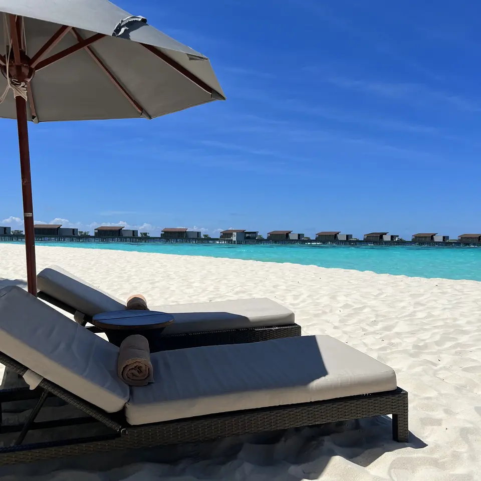 A lounger under a parasol facing the overwater villas