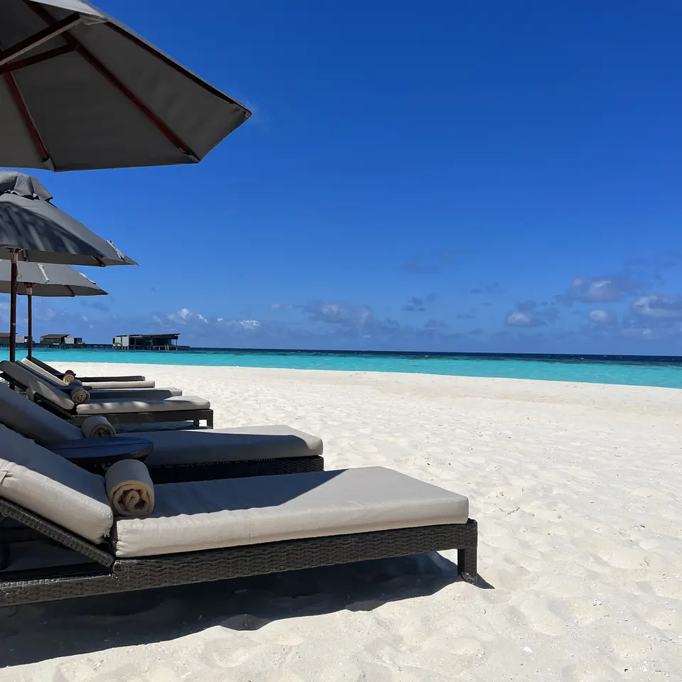 A row of loungers and folded parasols on the sand