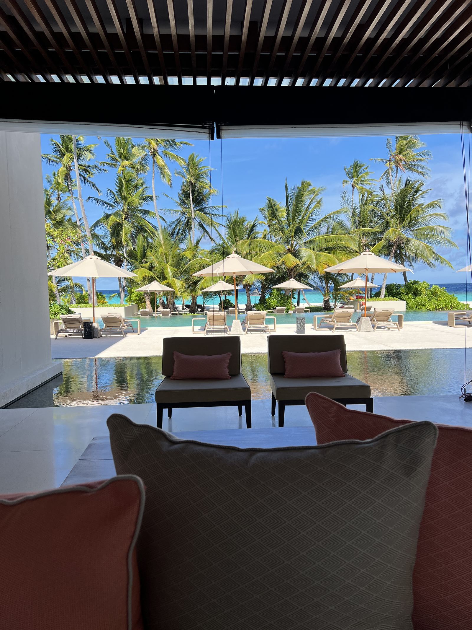 A shaded pavilion looking out over the pool and the parasols
