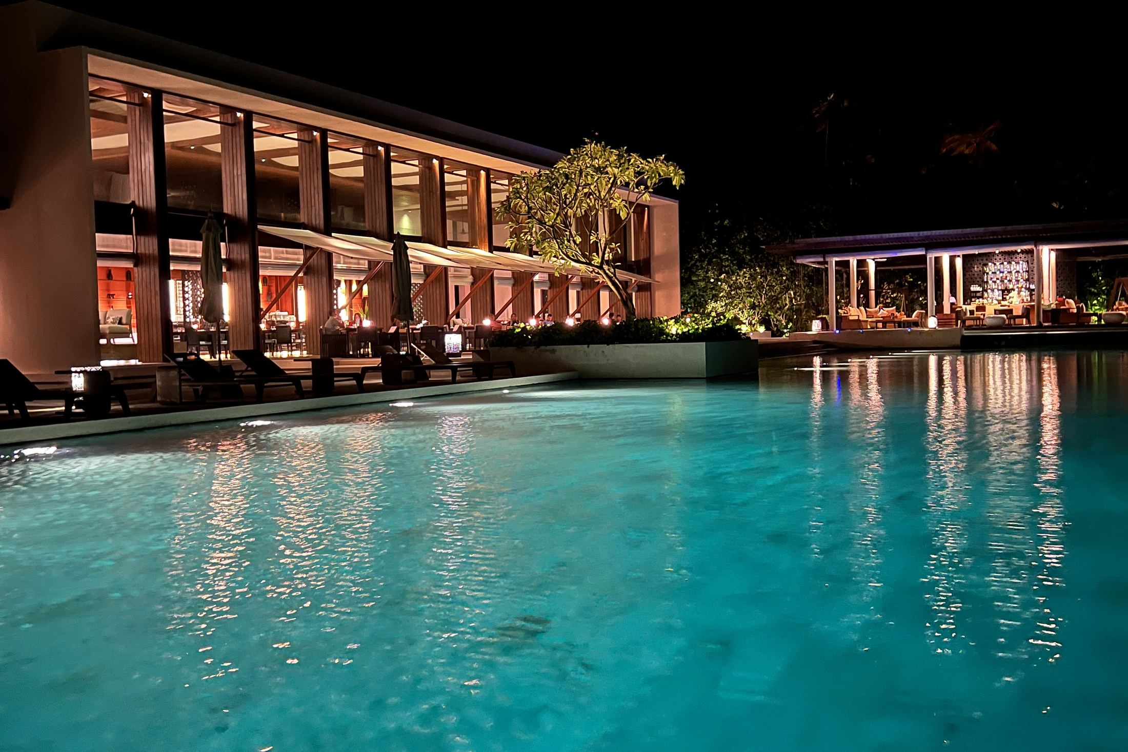 The main building at Hadahaa lit at night and reflected in the pool