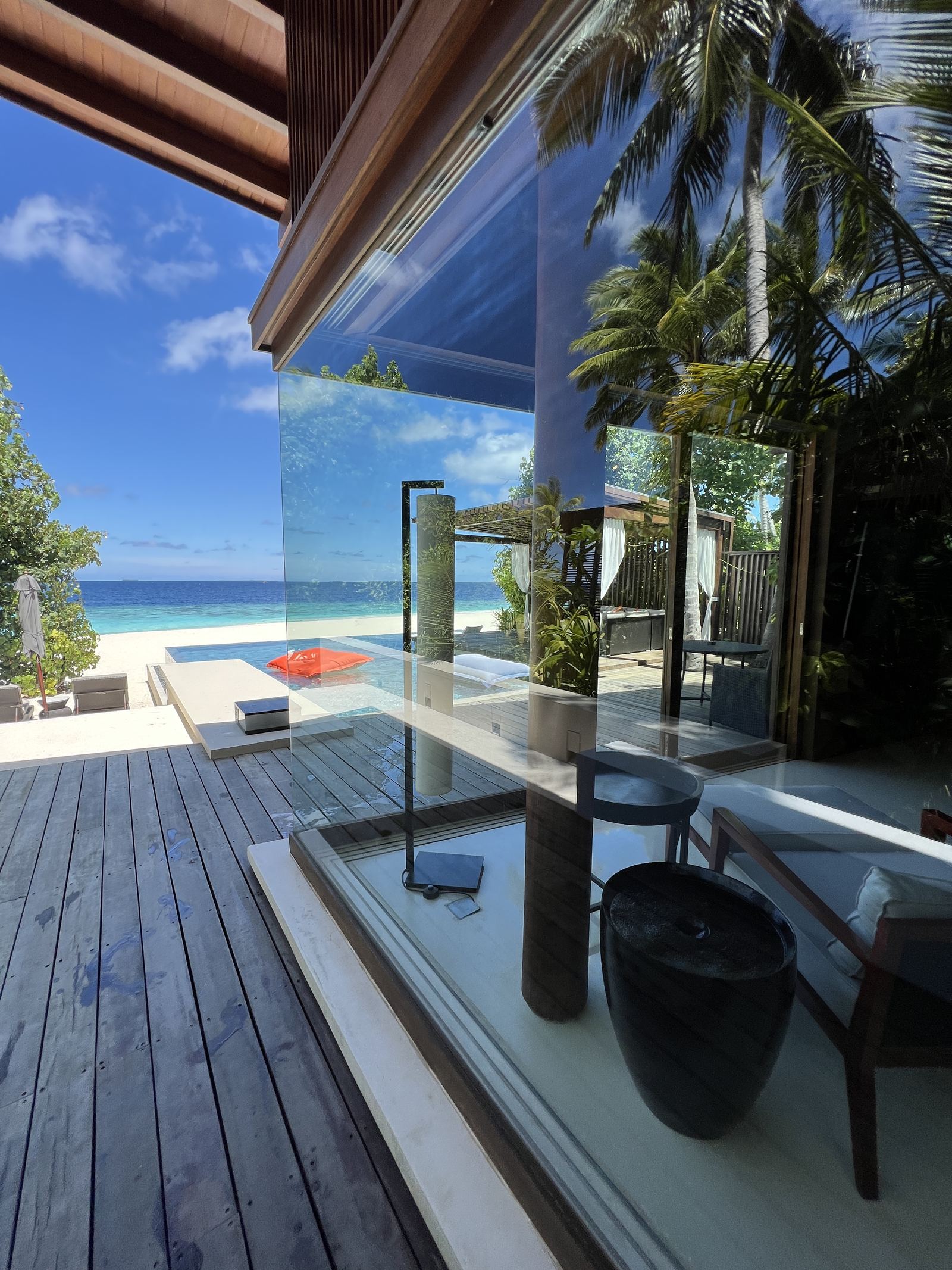 The deck of a beach villa with glass doors folded back on the sea