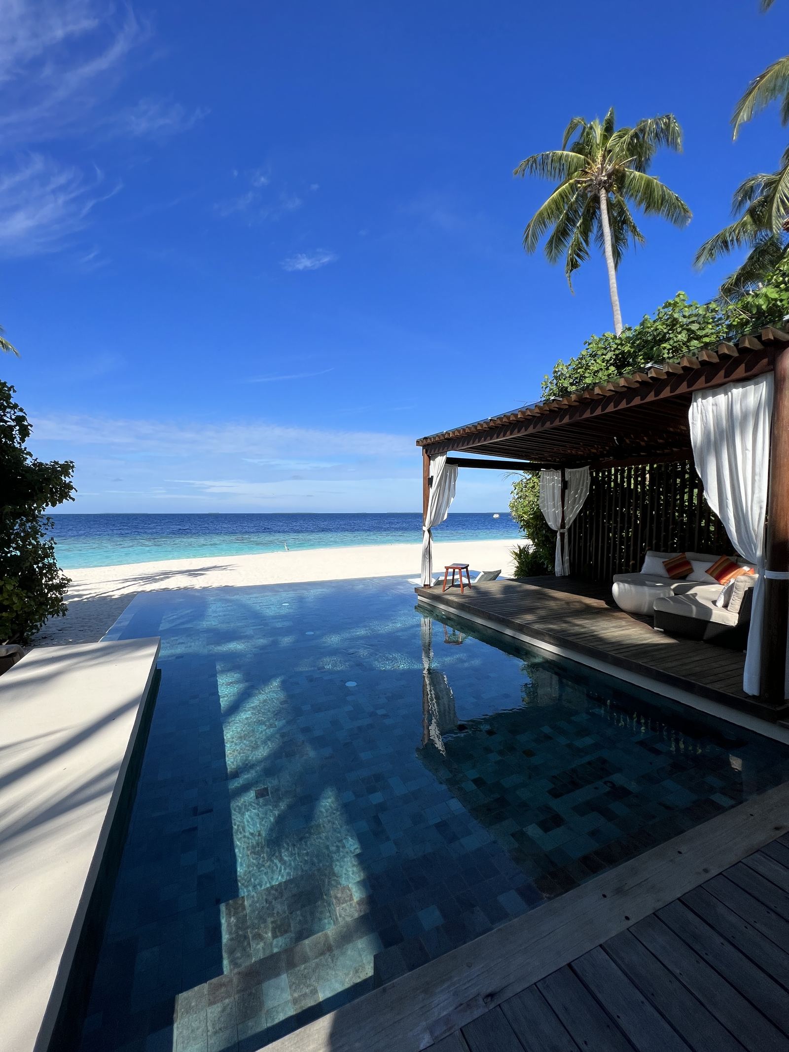 The pool of a beach villa with its pavilion and the lagoon beyond