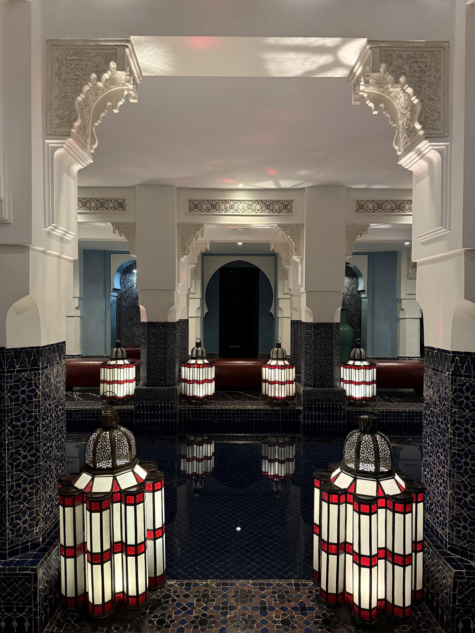 A white arch above a pool, with red and white lanterns on the tiled edge