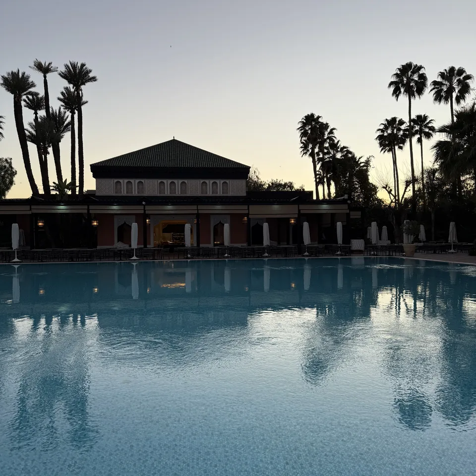 The pool of La Mamounia at dusk, with the palms and the pavilion reflected in the water