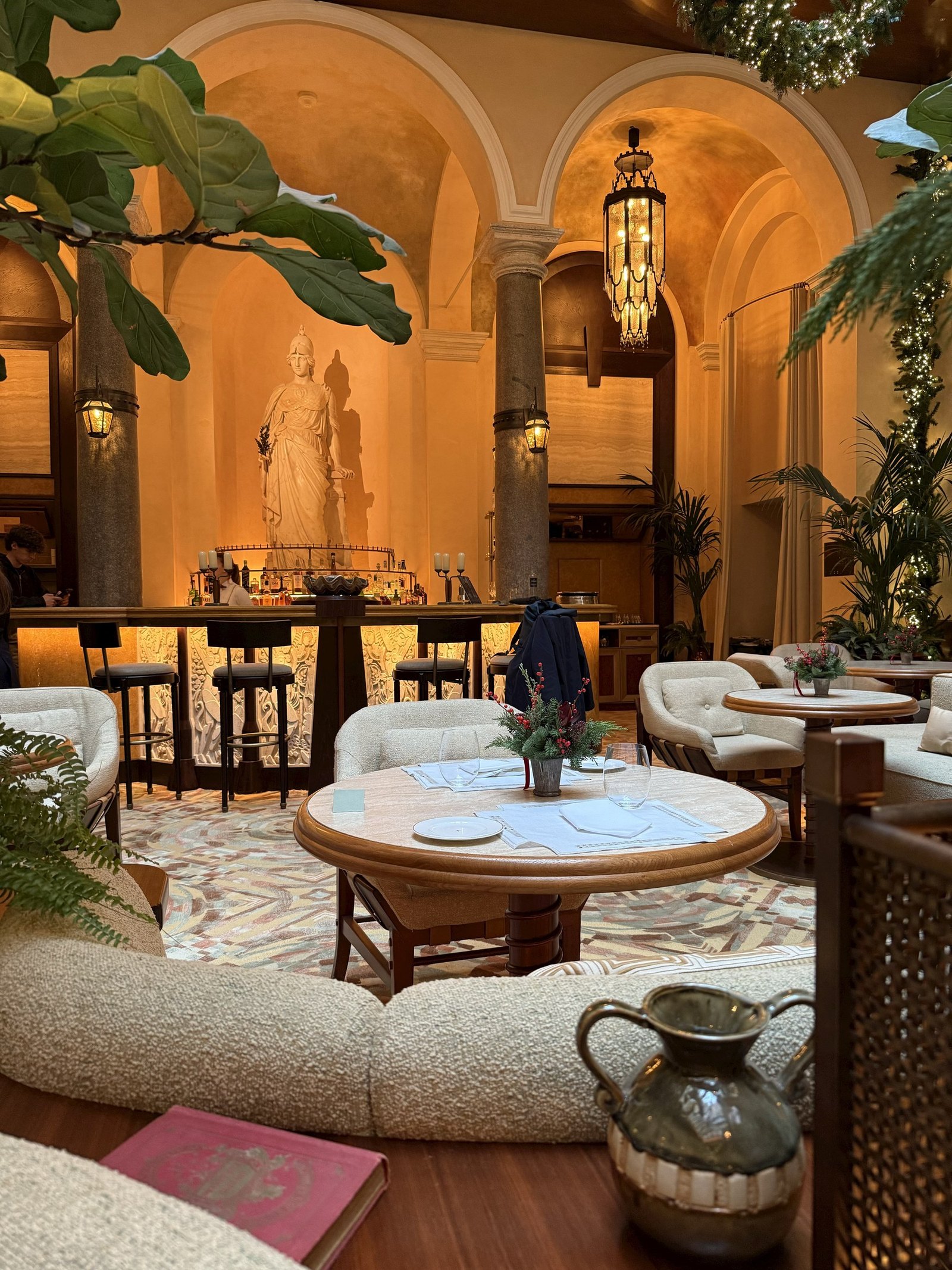 A lounge under an arched ceiling with a statue in a niche and plants
