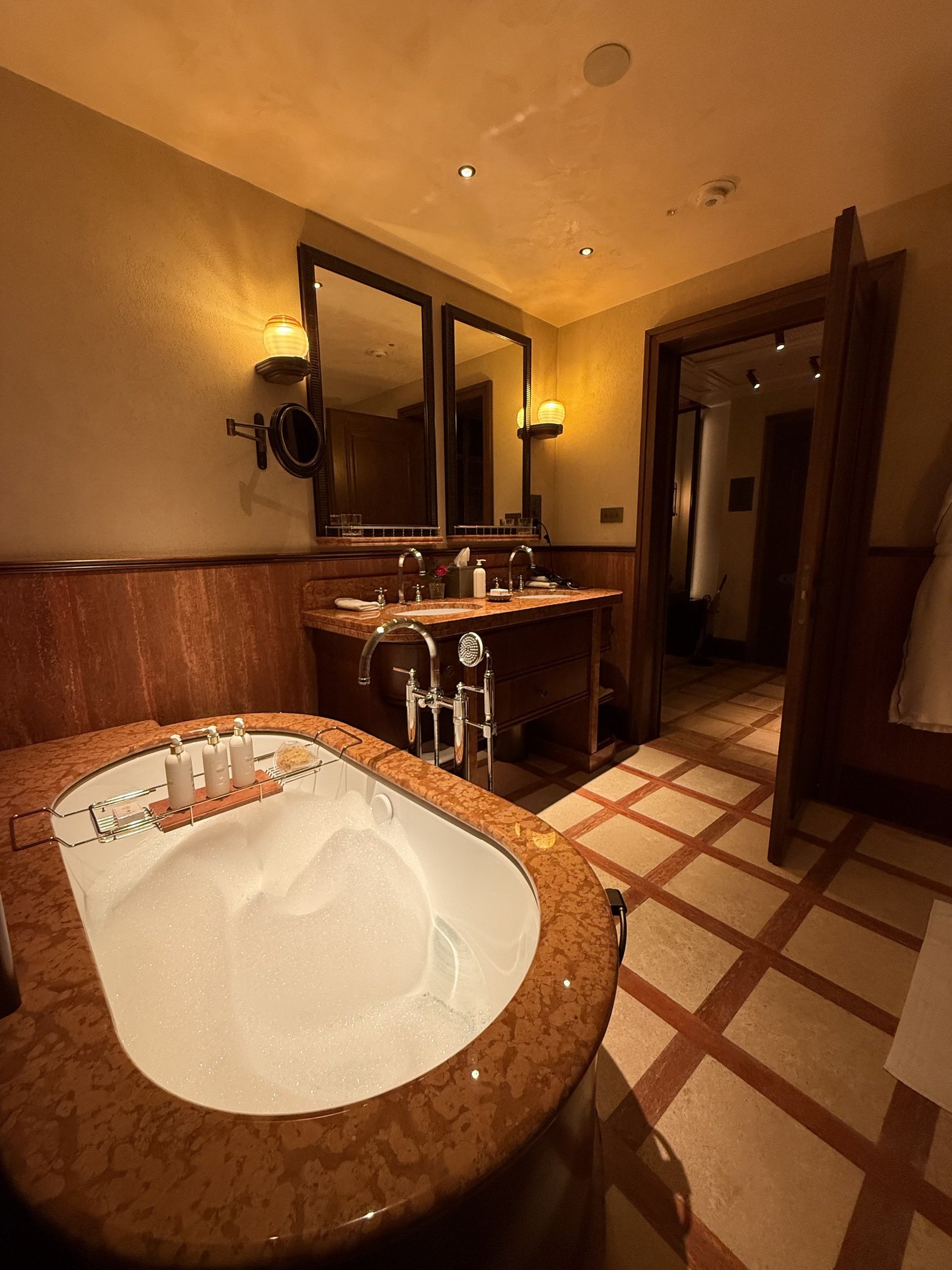 A bathroom with a tub, a timber vanity and a terracotta and cream checked floor