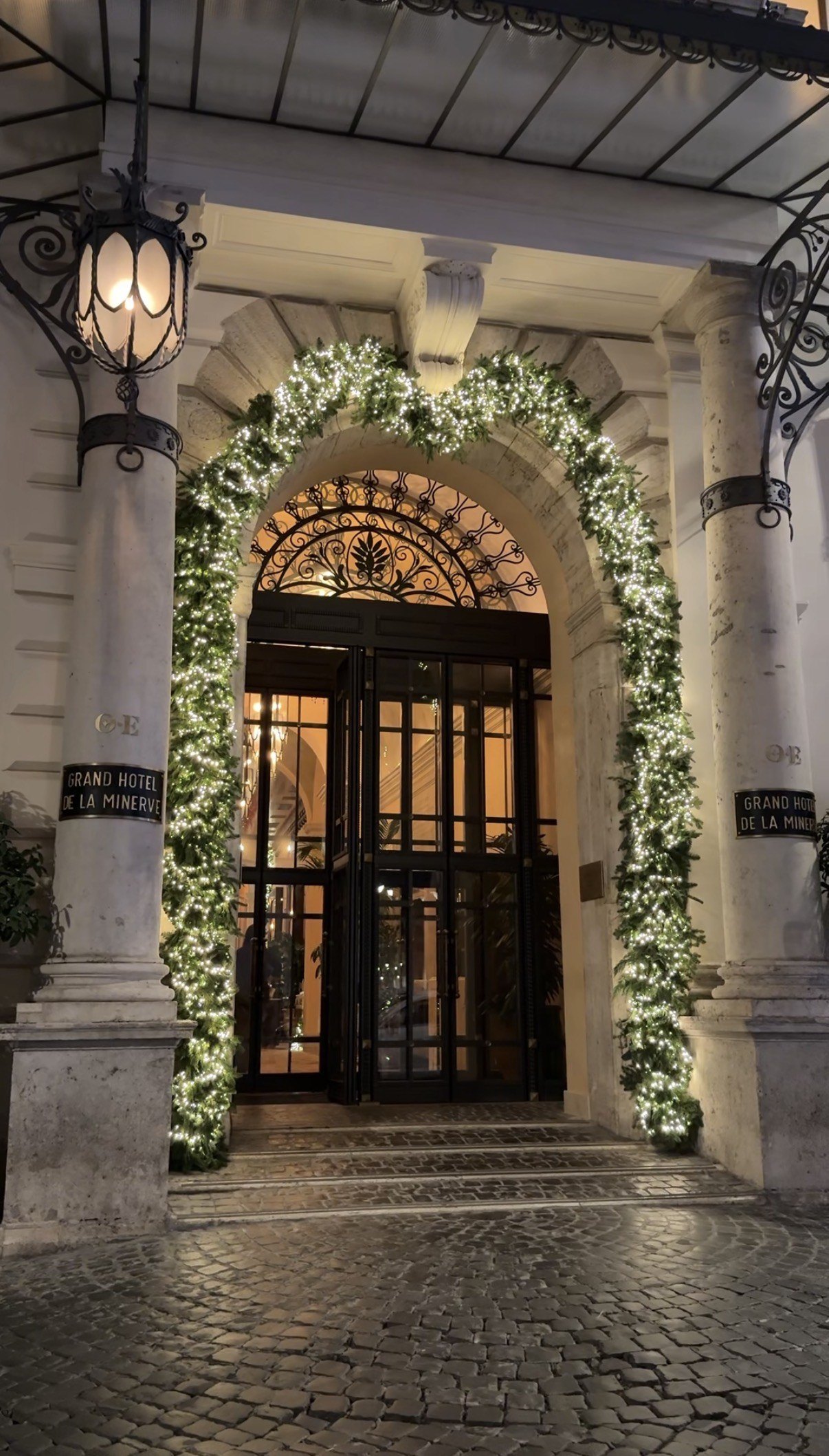 The entrance arch of La Minerva dressed with garlands and lit at night