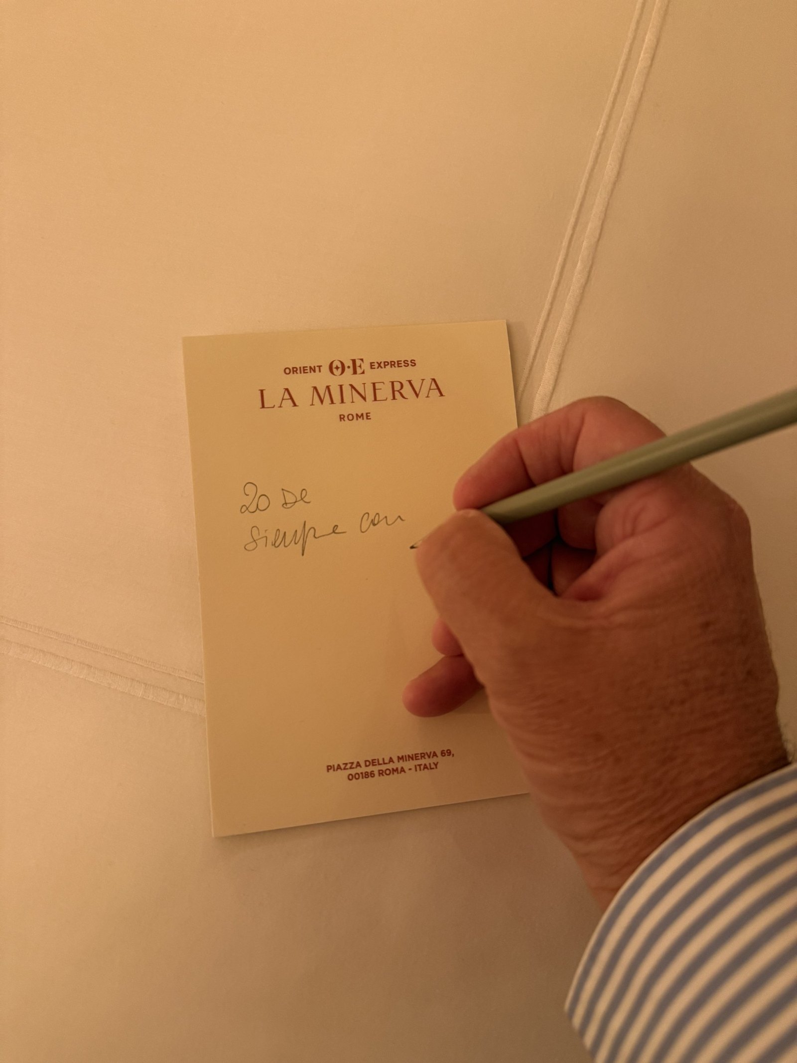 A hand writing on a sheet of Orient Express La Minerva notepaper